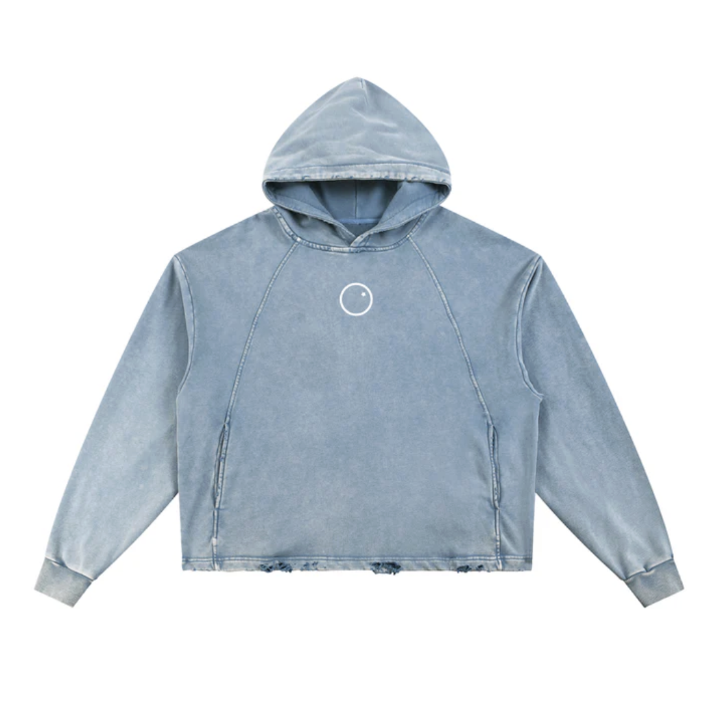 A light blue denim hoodie with a small white circle logo on the chest and distressed hems.