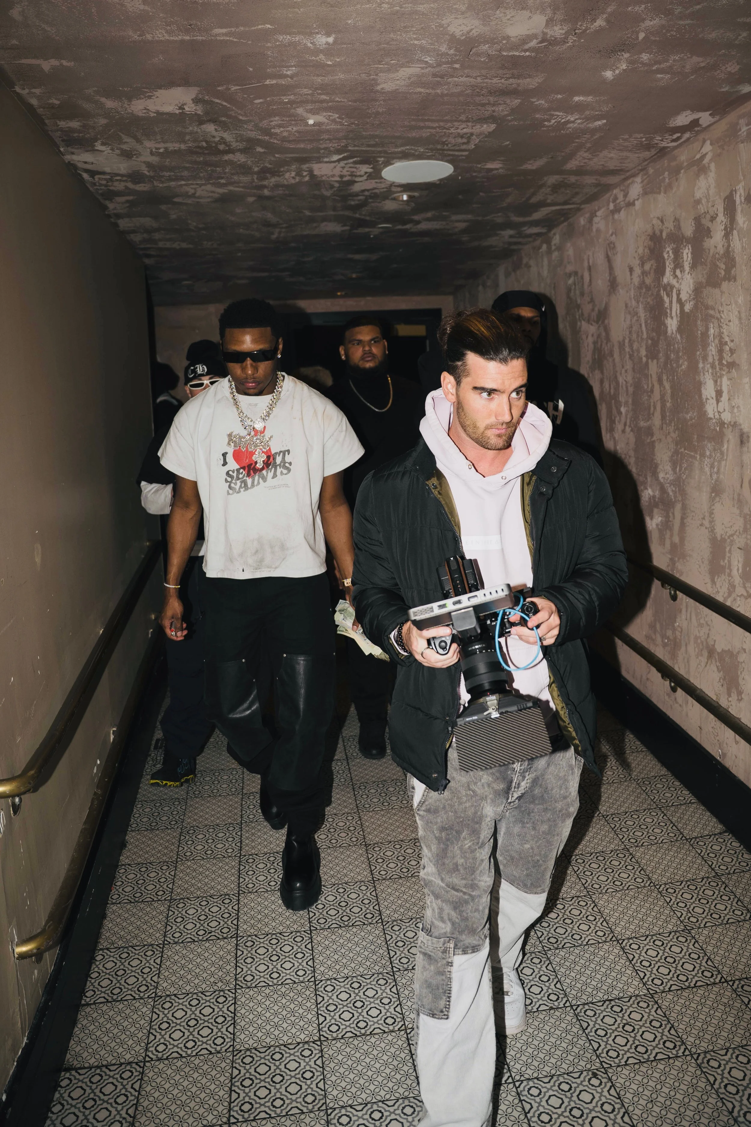 Nick Sheehan (@sh0tbynick) and ROB 49 the rapper walking through a dimly lit hallway. Nick is in front holding a camera.