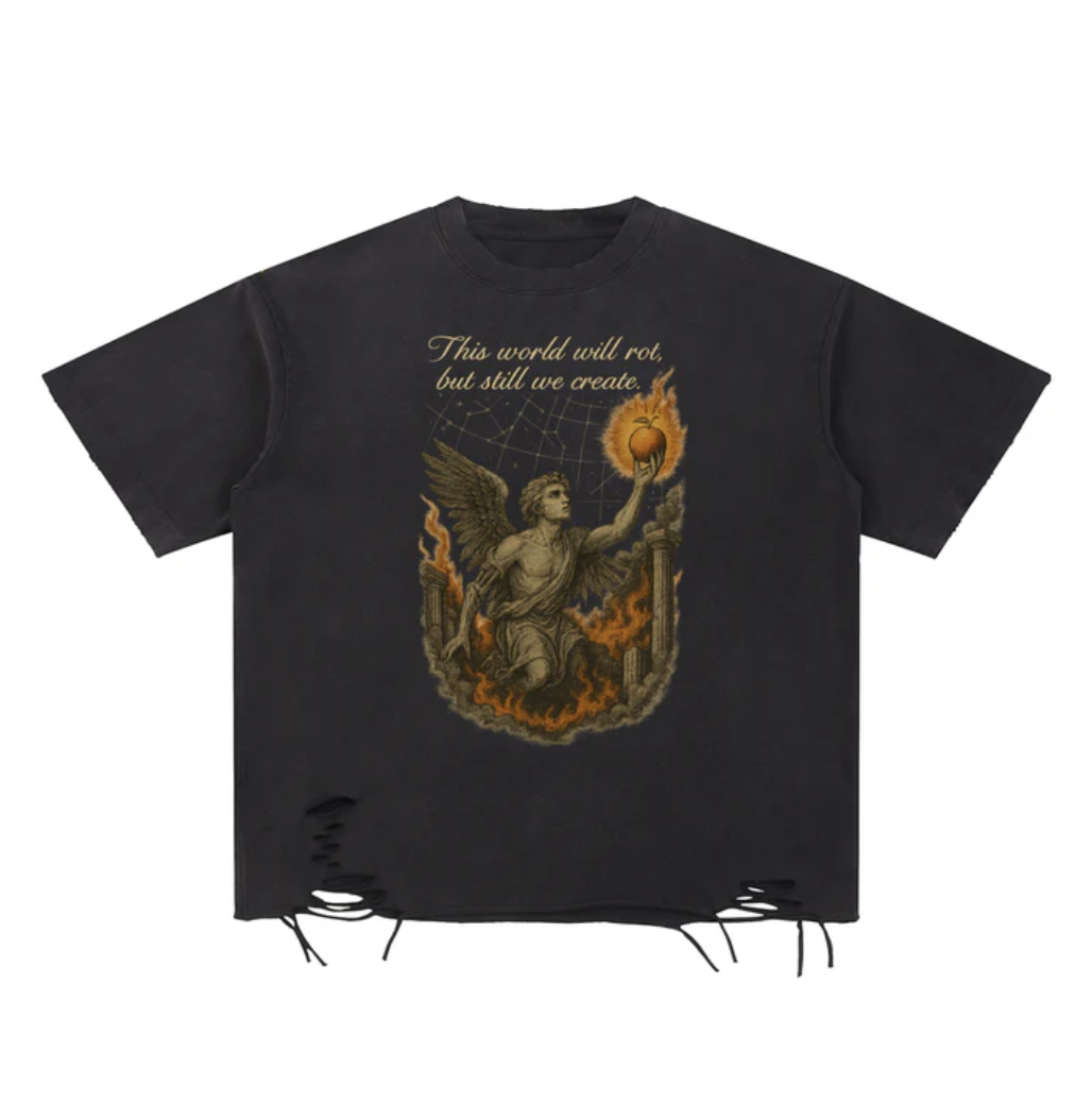 Black T-shirt with a graphic of an angel holding a flaming orb and the text "This world will rot, but still we create." The design includes elements of fire and ruins.
