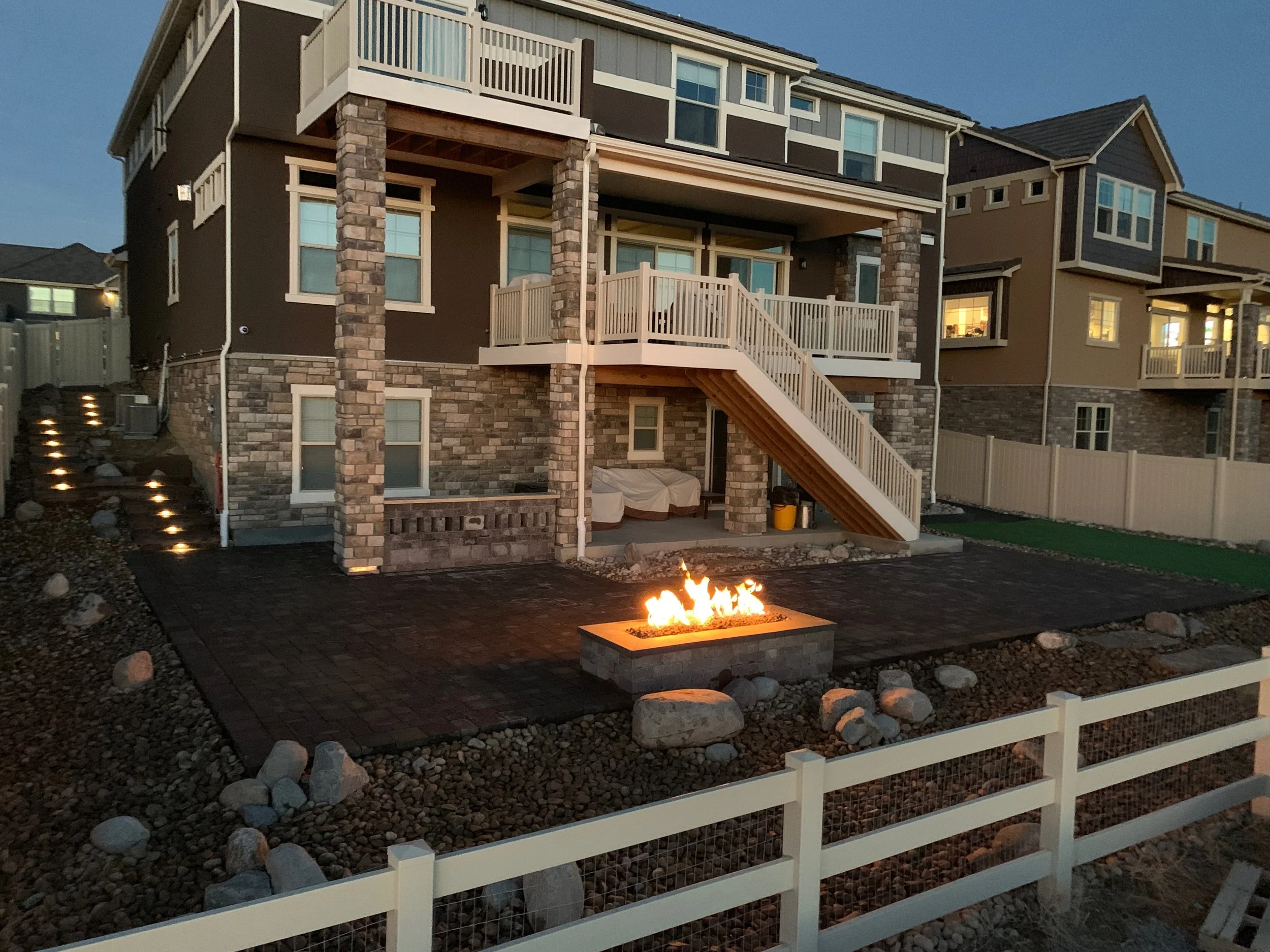 View at dusk of back of home with patio and burning fire pit