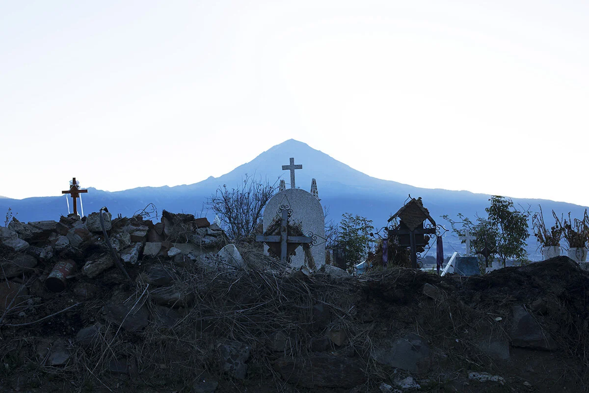 A graveyard sits against the backdrop of Popocatépetl, an active volcano,in the village of Cuijingo, where a large portion of the male population goes to Canada as migrant workers. Last fall, Julio Lucio Robledo, who had been going to Canada for 26 years, died near London, ON after falling down the stairs in his bunkhouse. His brother, who is also a migrant worker, says his body stayed in Canada for a month and a local church had to pressure the authorities to repatriate him to Mexico.