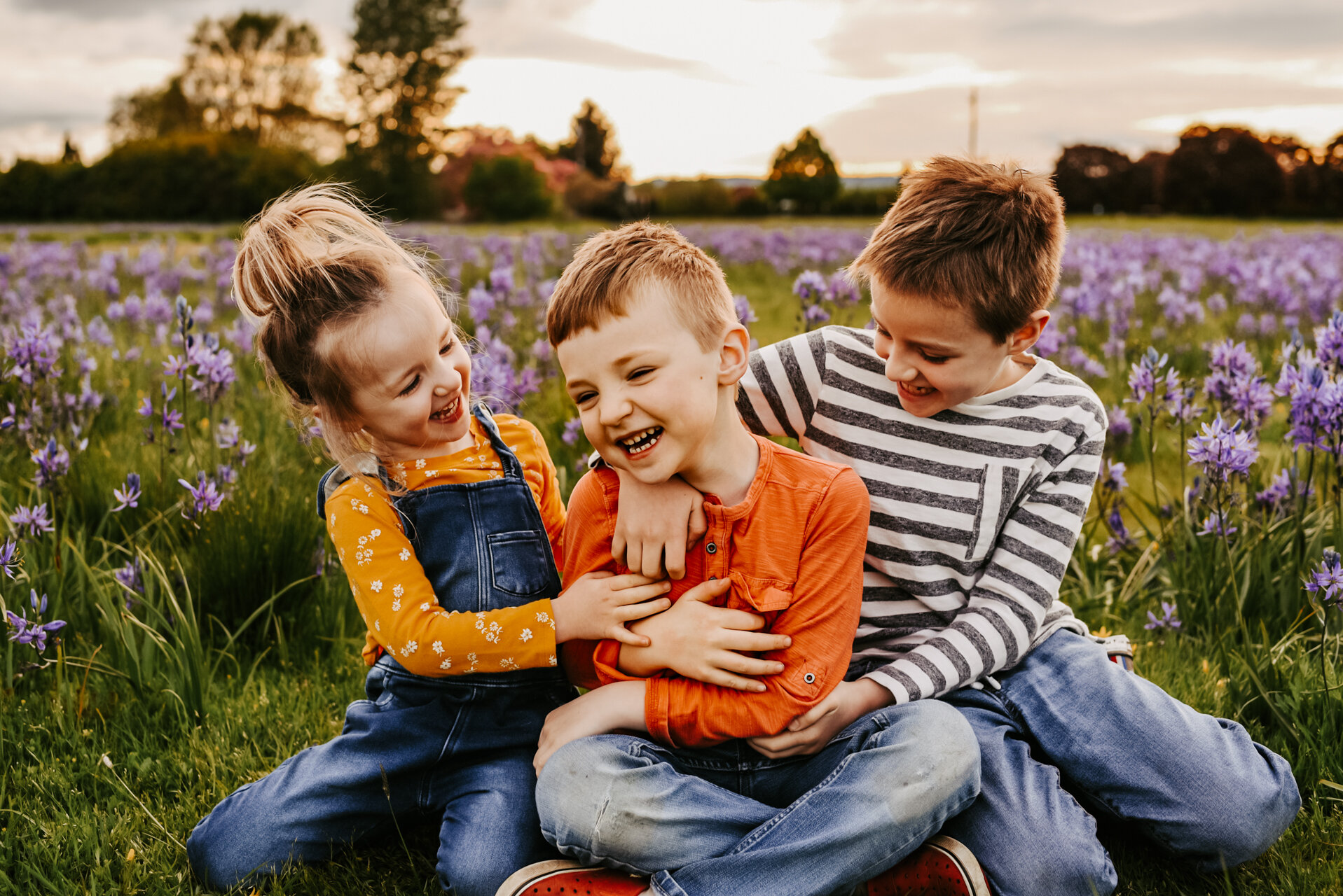 Sibling tickle each other in field of purple flowers