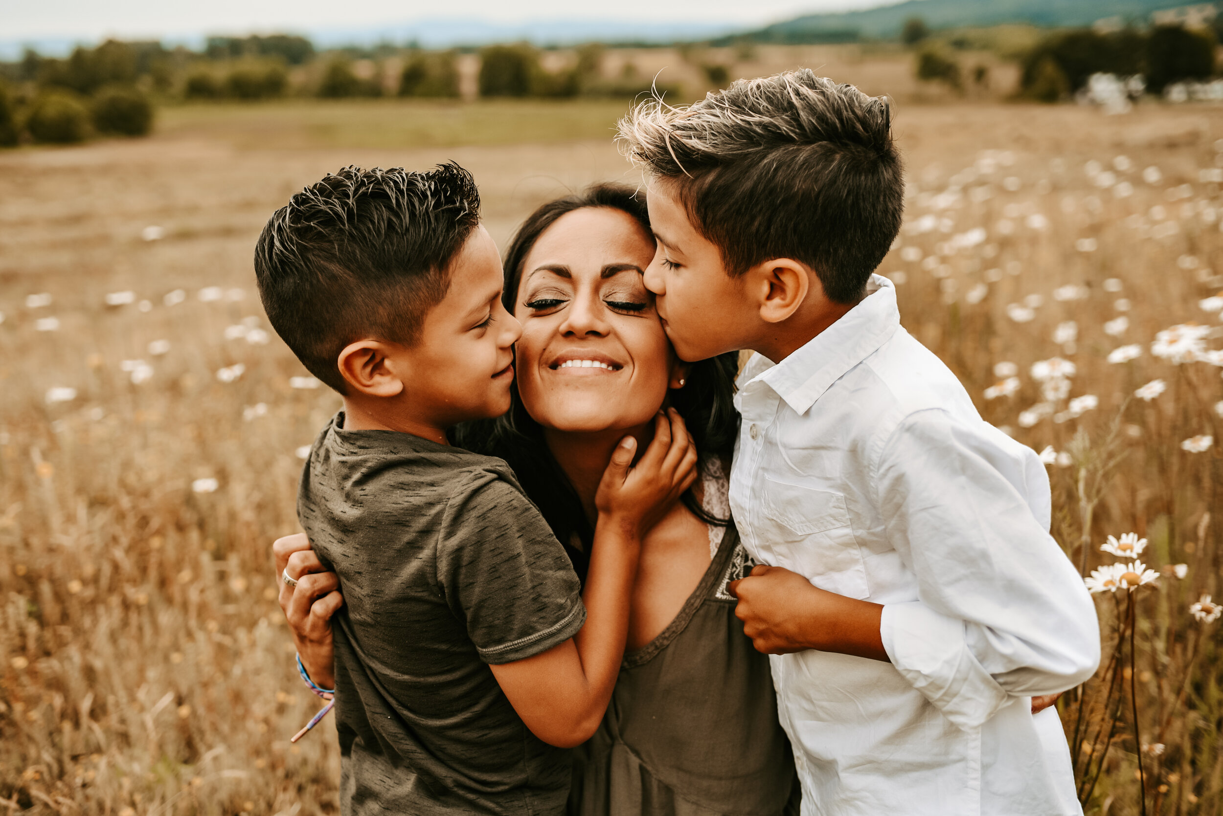 Mother gets kissed on each cheek by two sons
