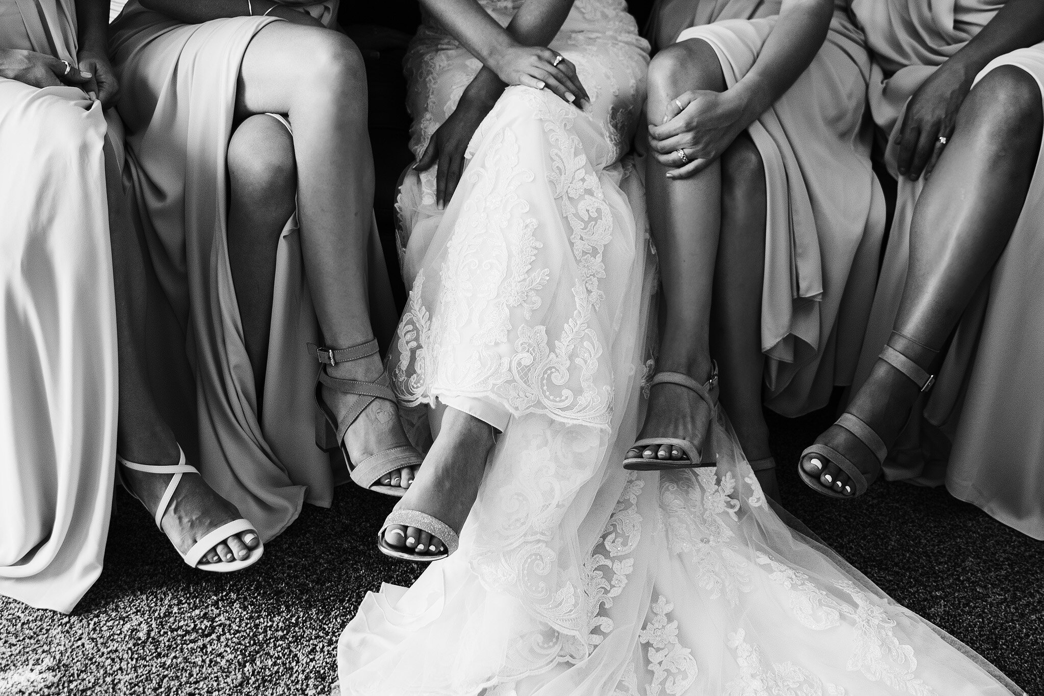 Bride and bridesmaids legs crossed in beautiful dresses