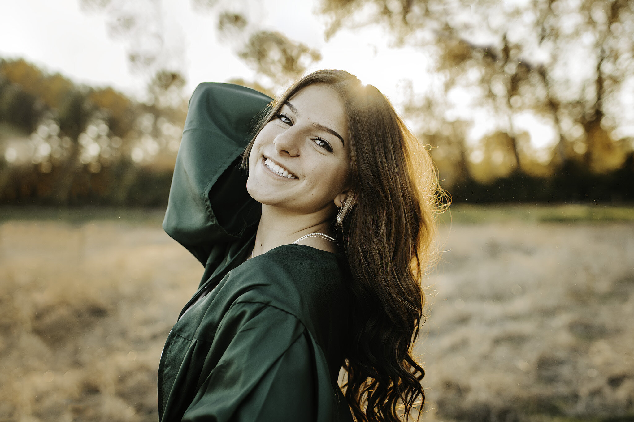 Senior girl in green graduation gown smiling at photographer