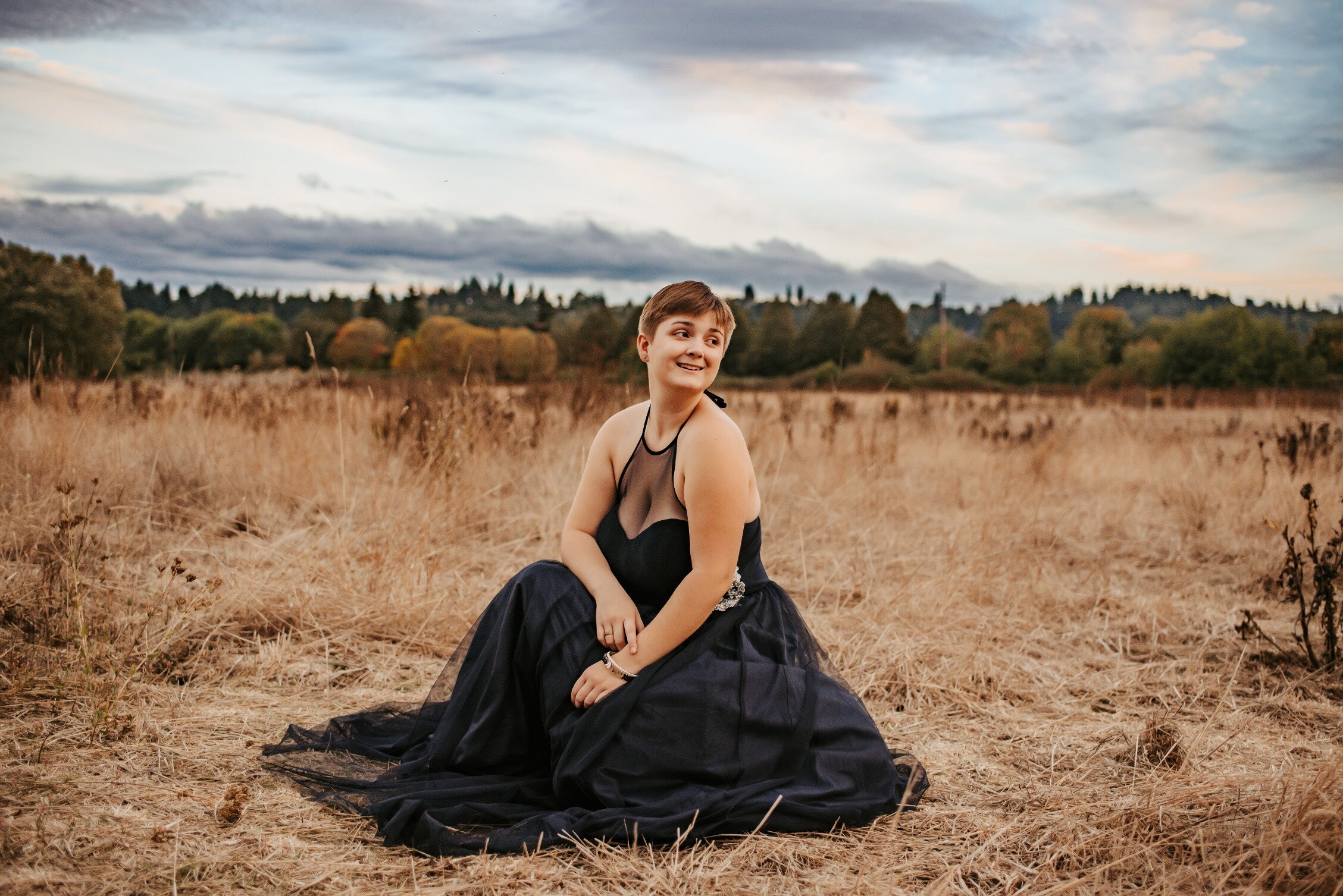 Senior girl in formal dress at sunset in a brown field