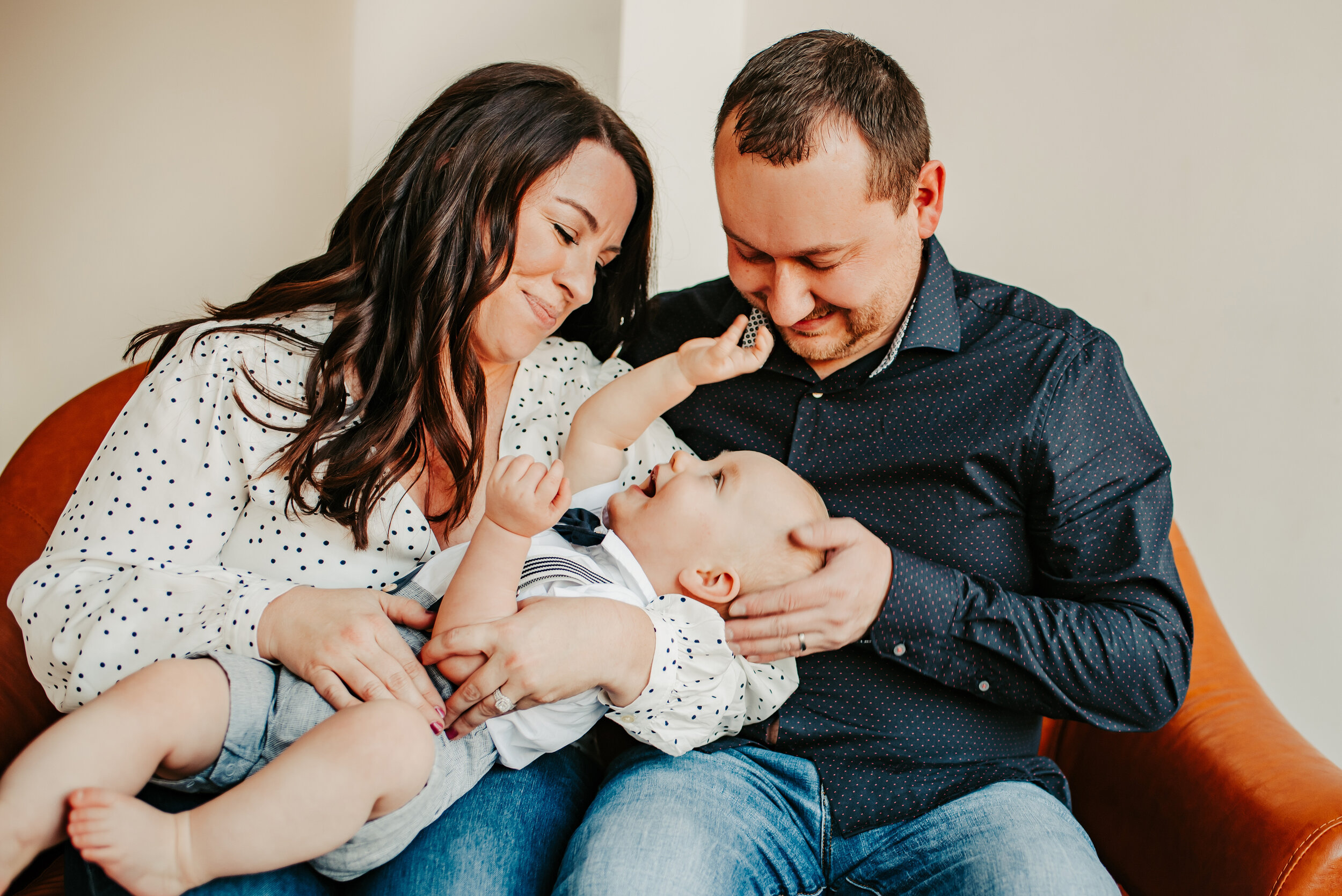 Family sitting on a couch playing with their baby boy