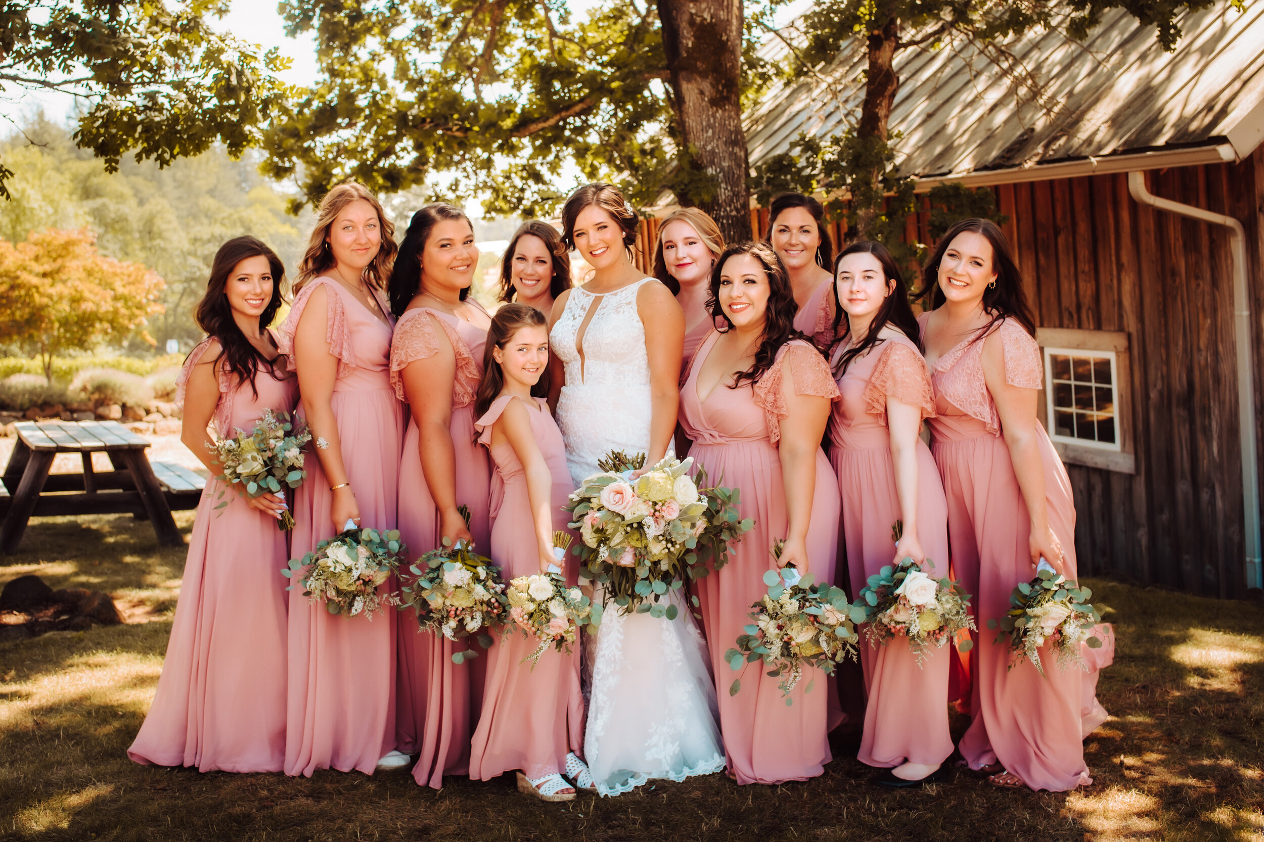 Bride and bridesmaid hold bouquets looking at photographer