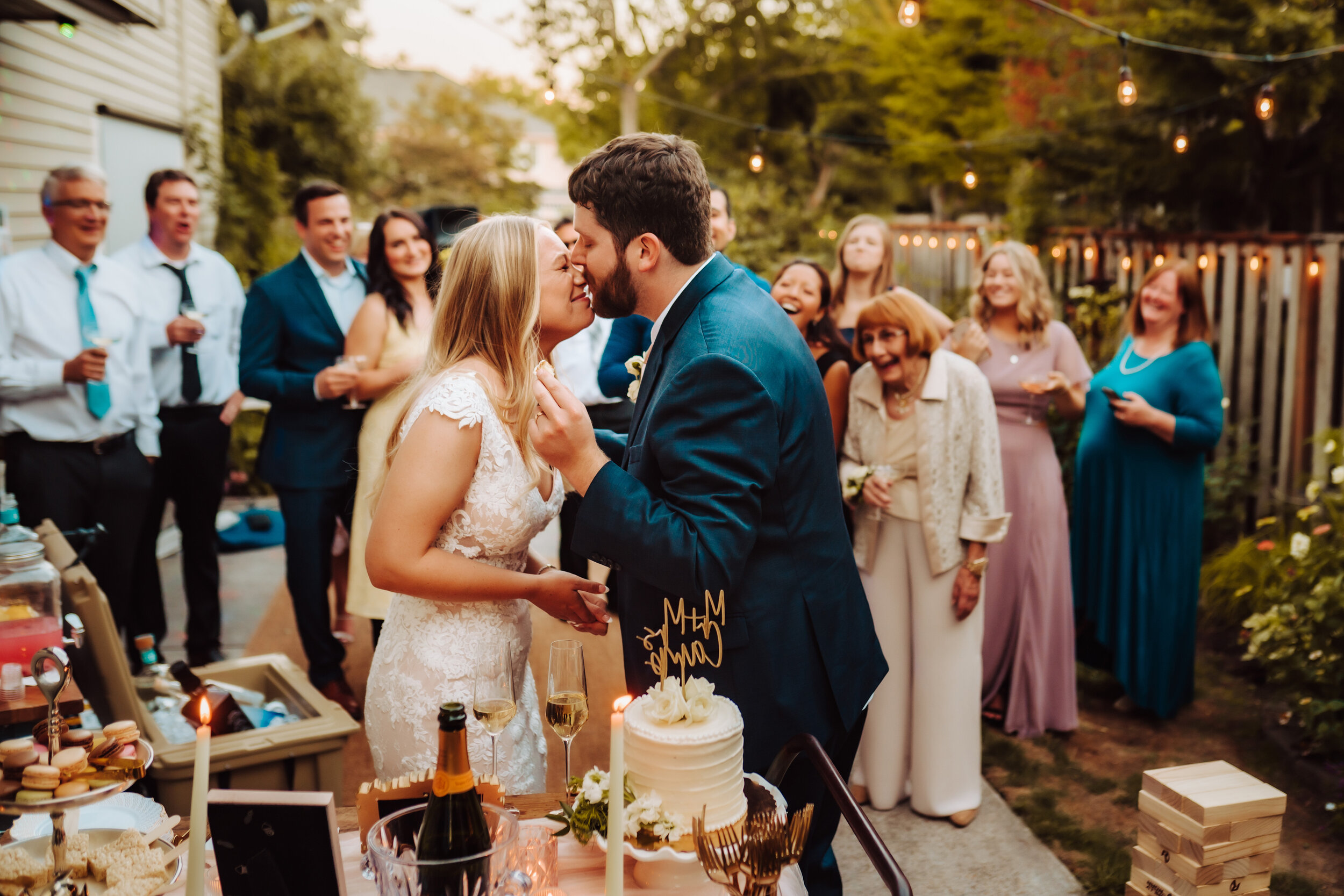 Groom kisses bride's nose after getting cake on her nose at their wedding