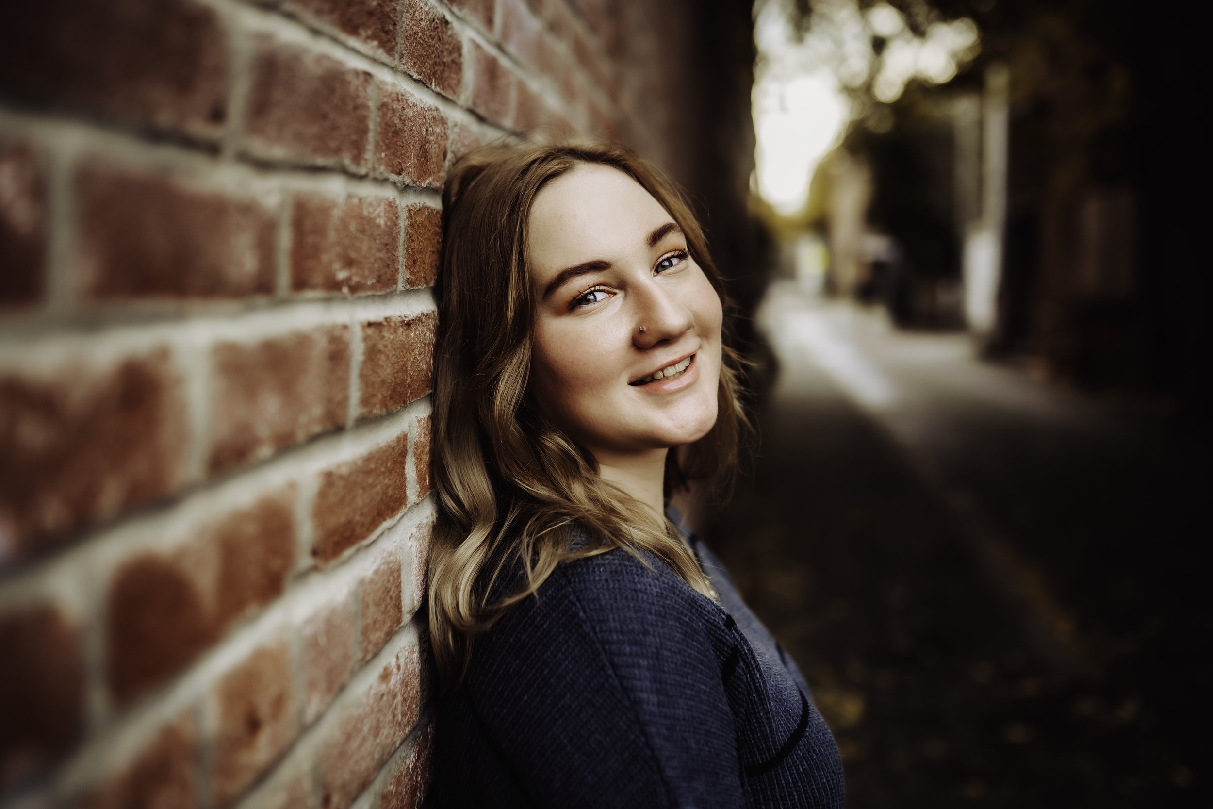 Senior girl leaning against red wall