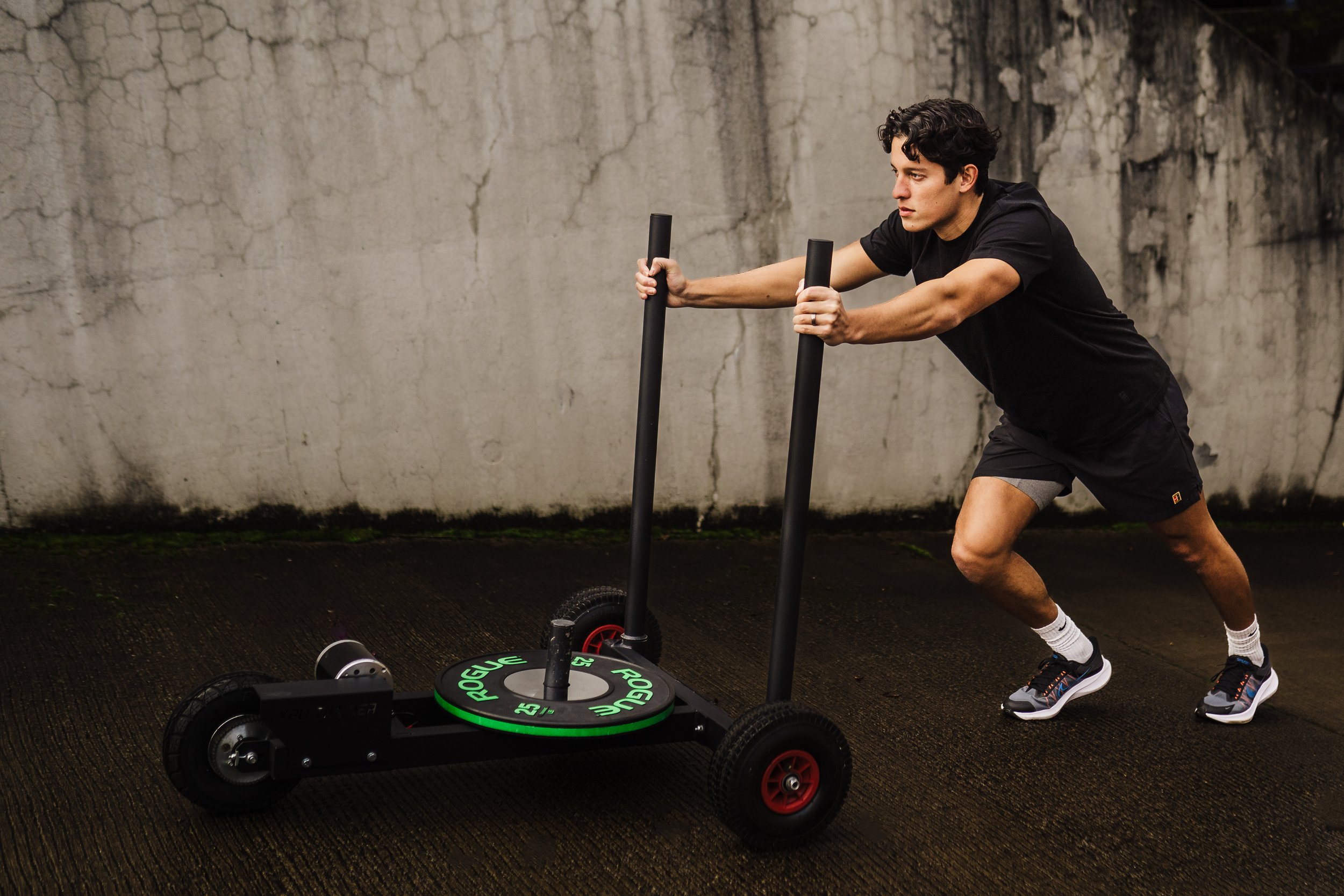 Athlete pushes weight machine up hill outside