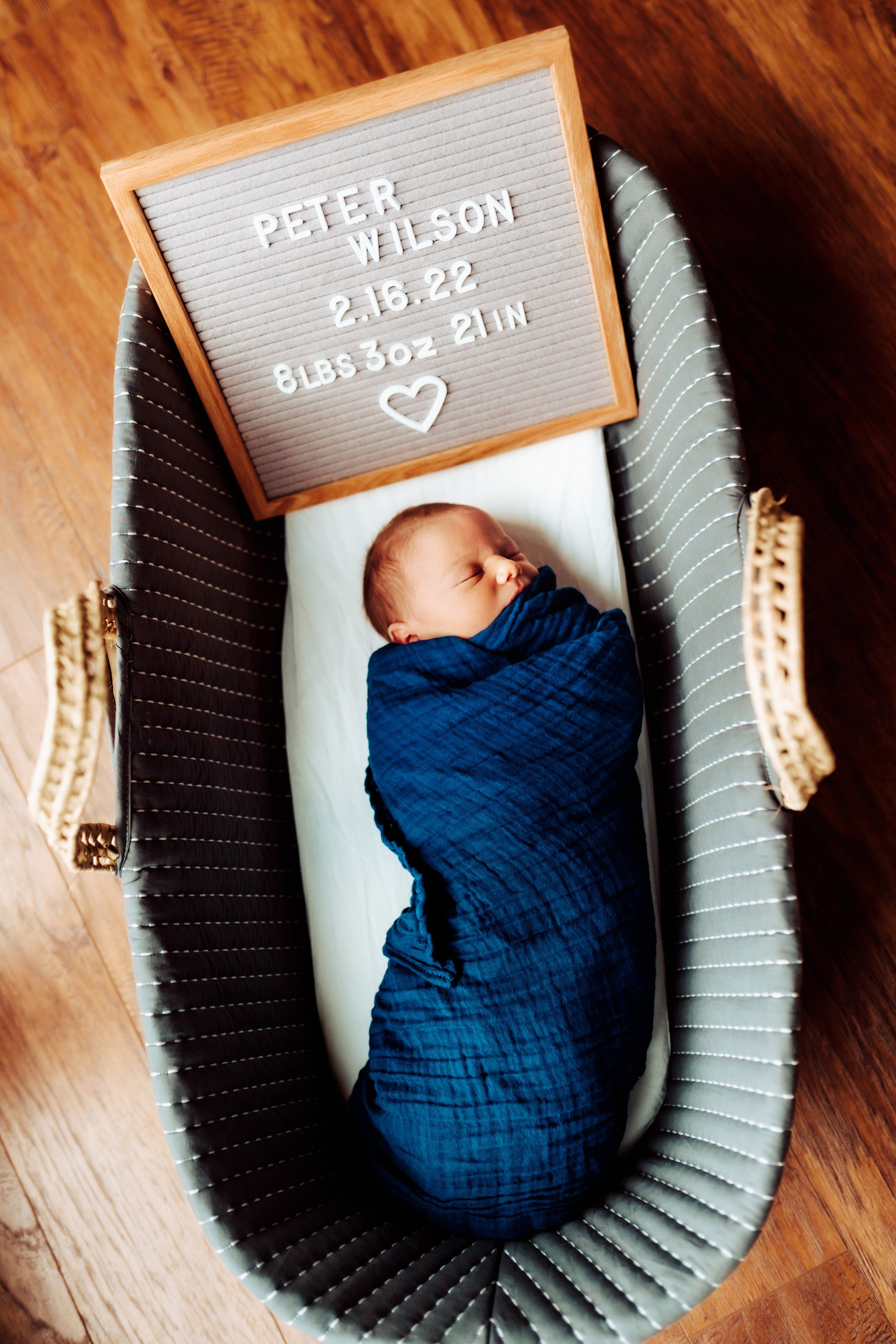 Baby Peter lays in Moses basket with letter board of his newborn stats