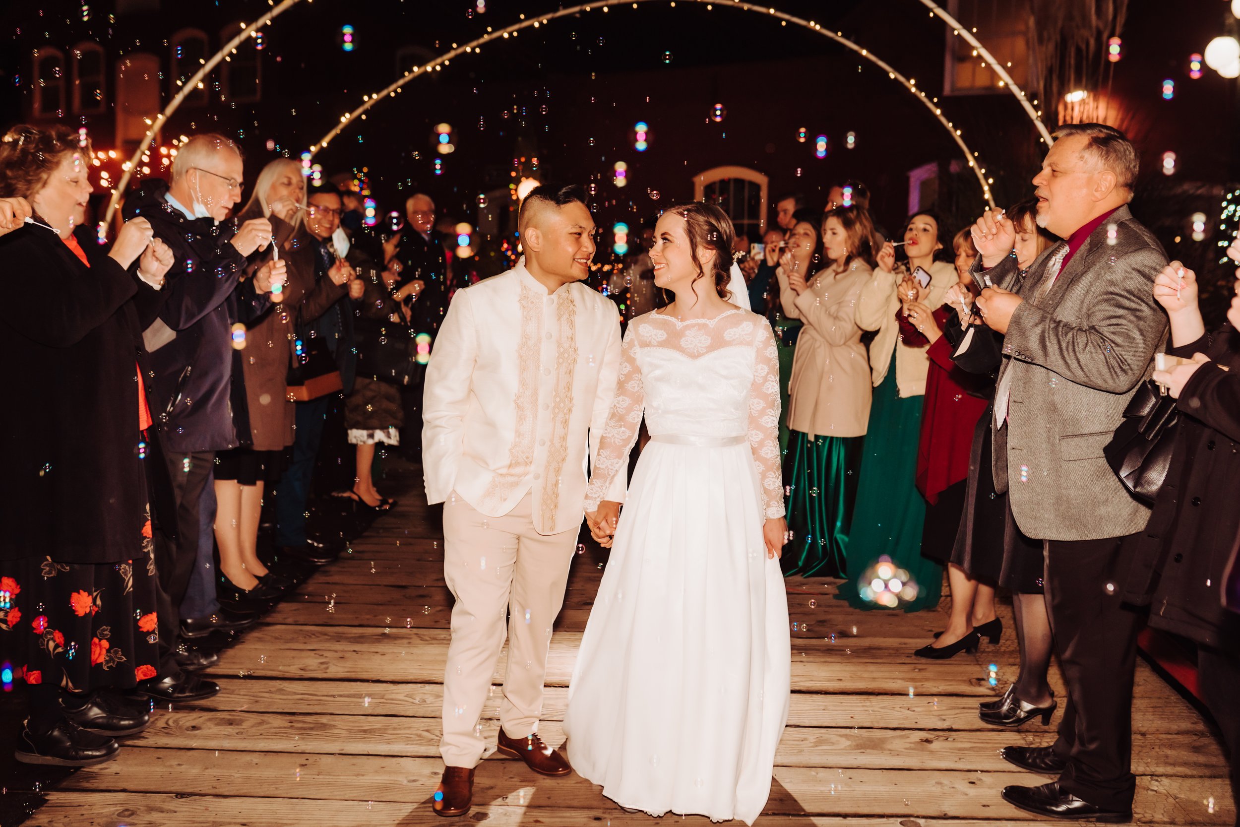 Bride and groom exit their wedding through a sea of bubbles