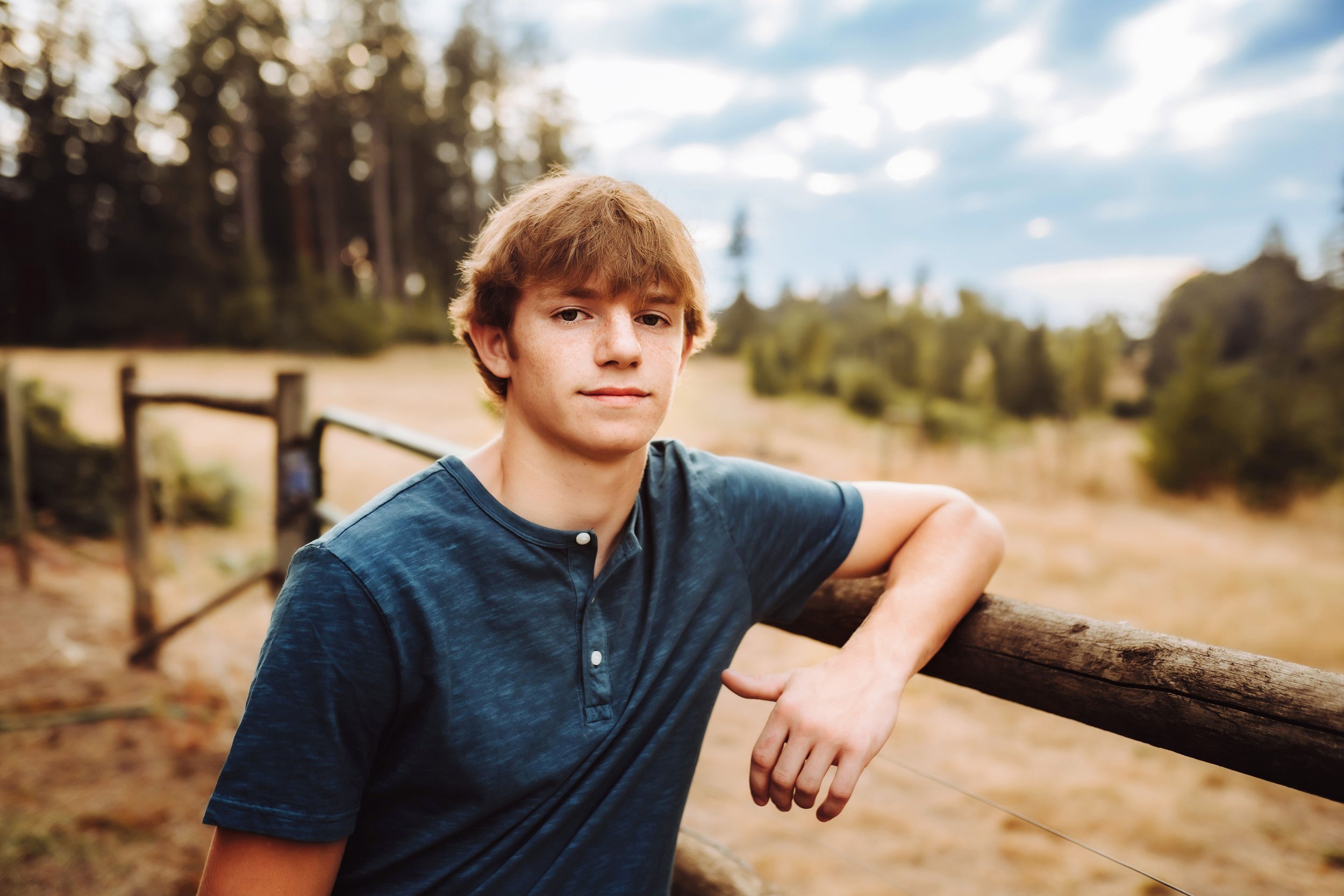 Senior boy leaning on horse fence.