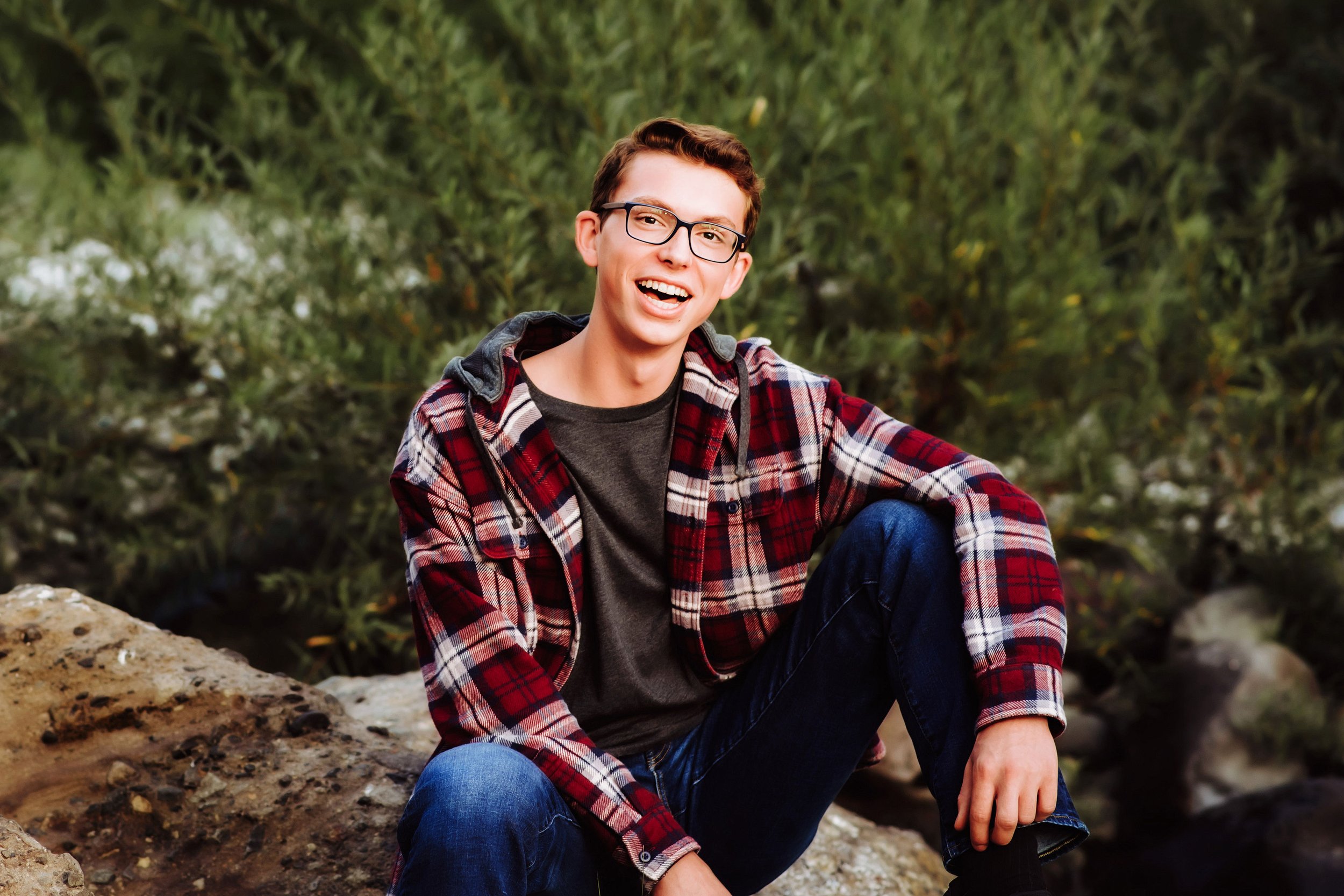 Senior boy sitting on rocks smiling