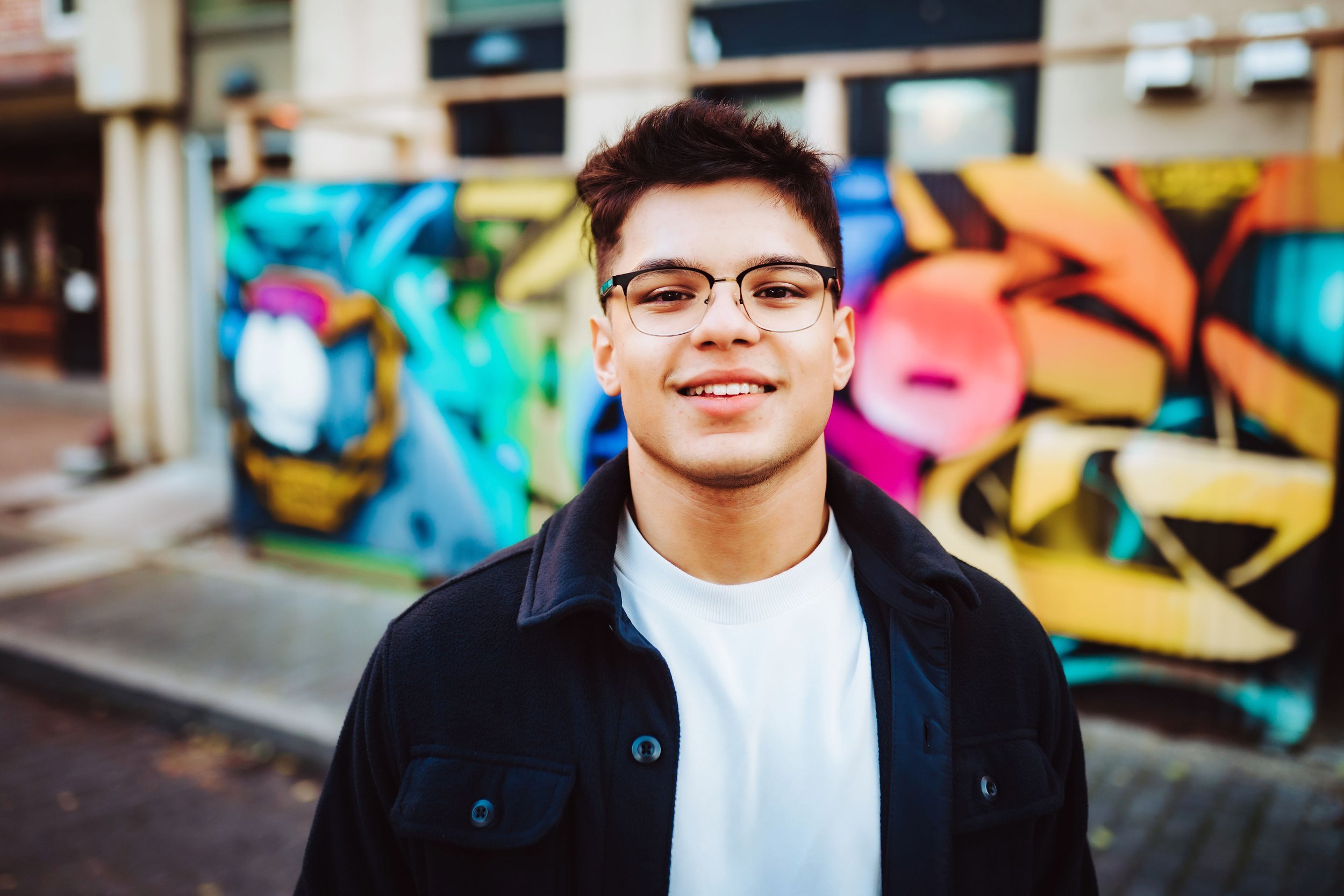 Senior boy smiling in front of colorful wall