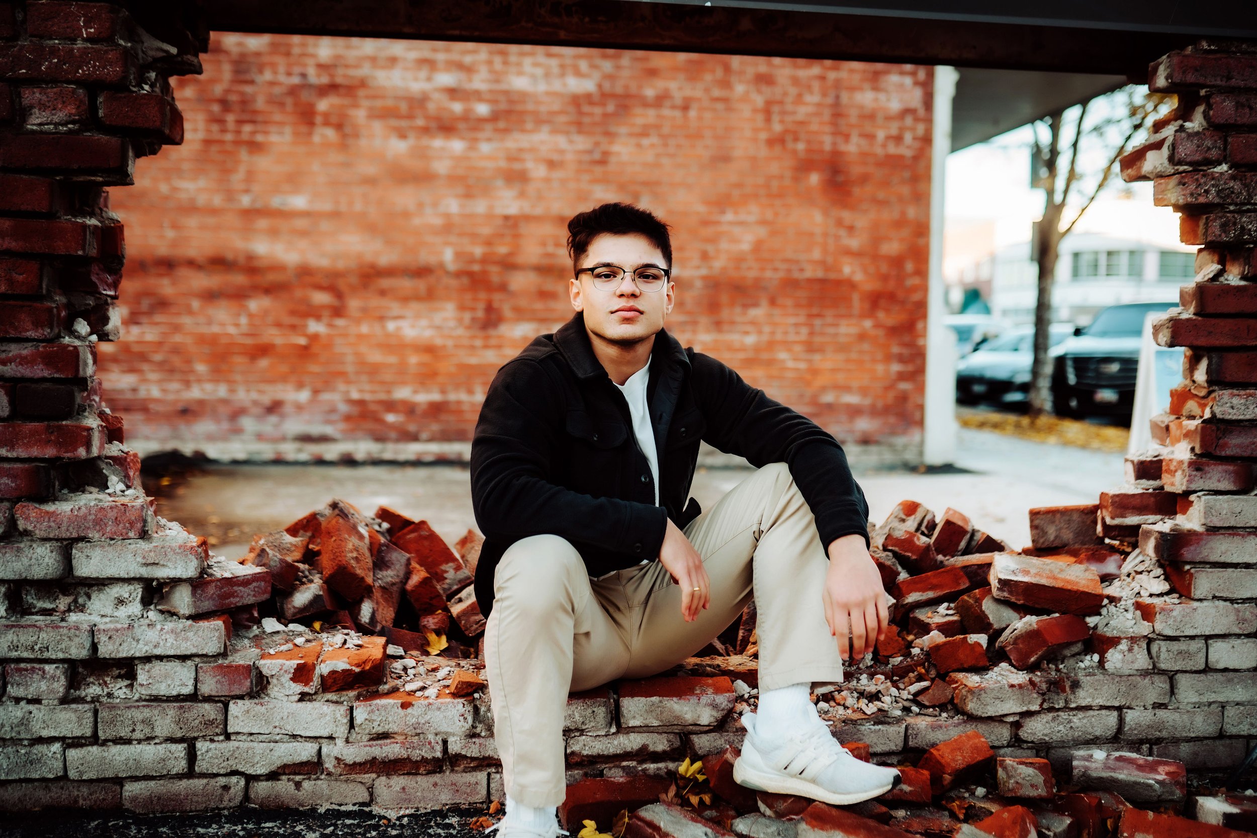 Senior boy sitting on destroyed bricks