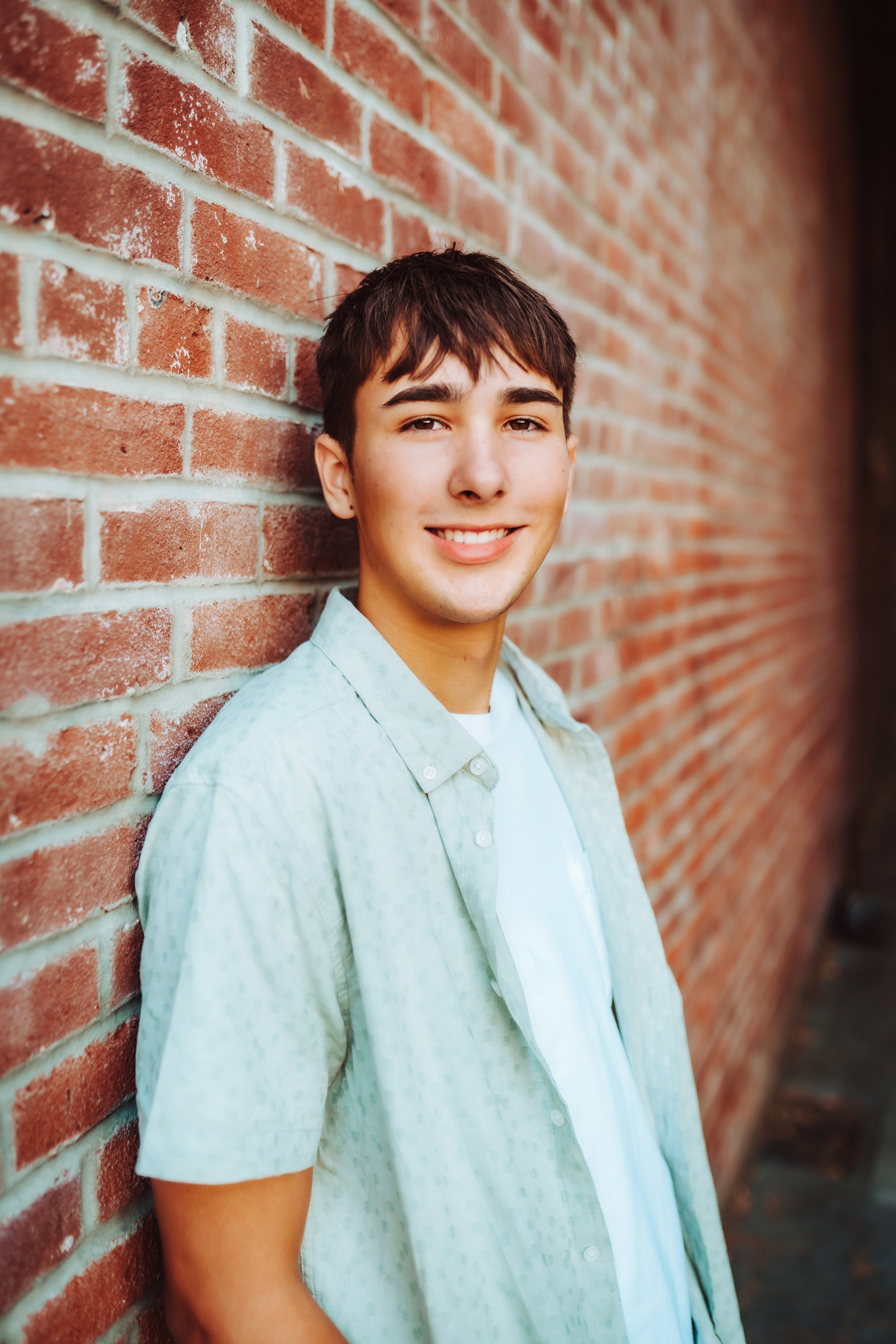 Senior boy leaning against brick wall