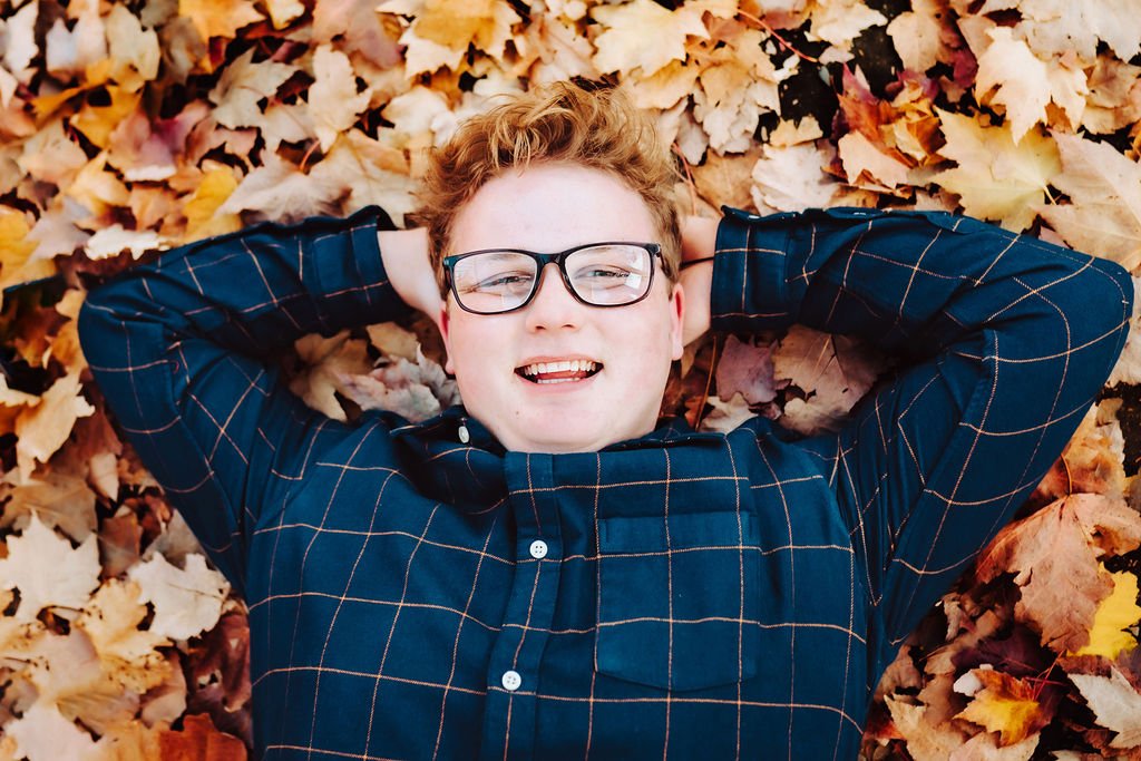 a senior in high school laying in a pile of leaves