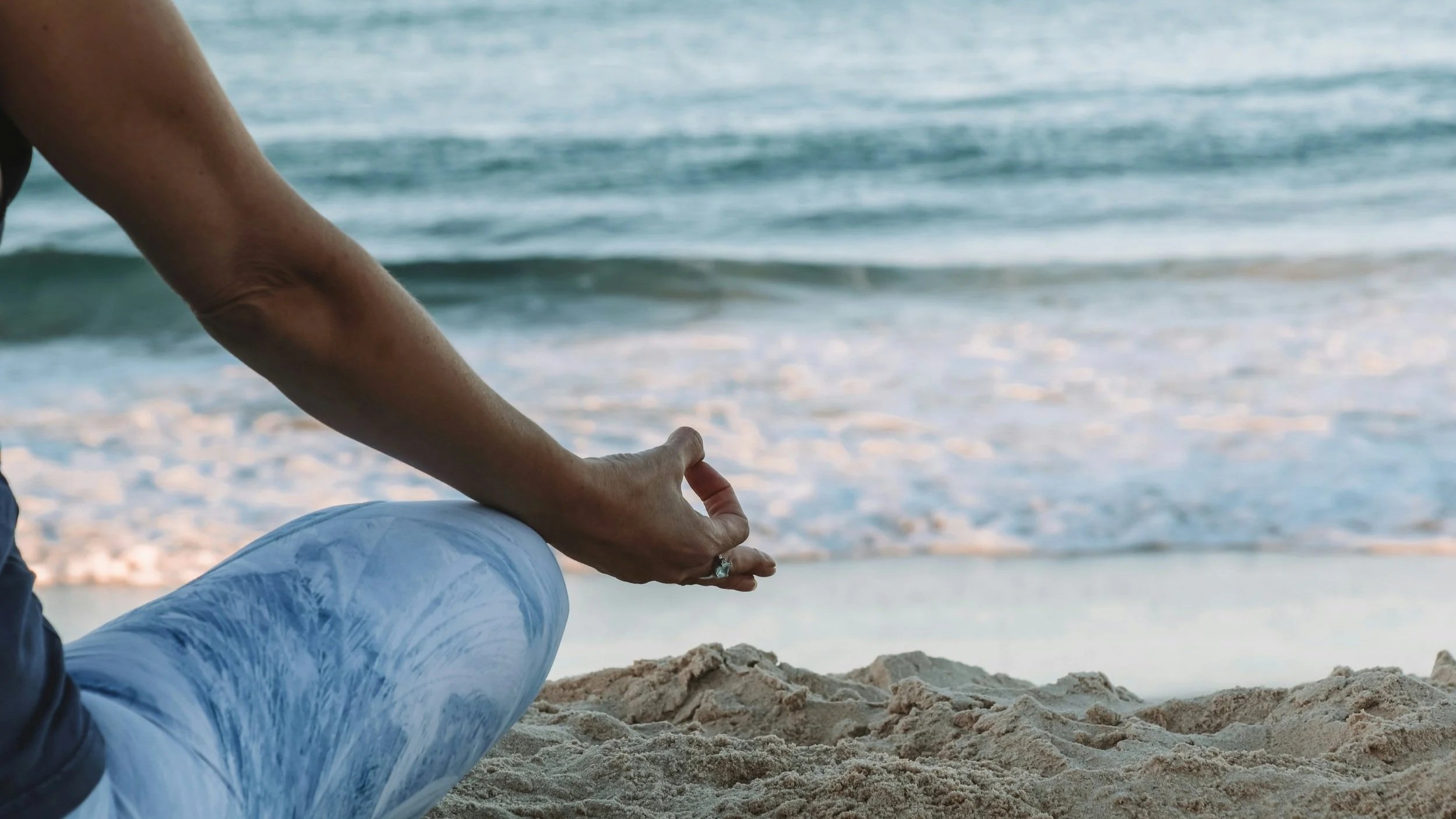 image of woman sitting on the beach depicting how to do somatic meditation