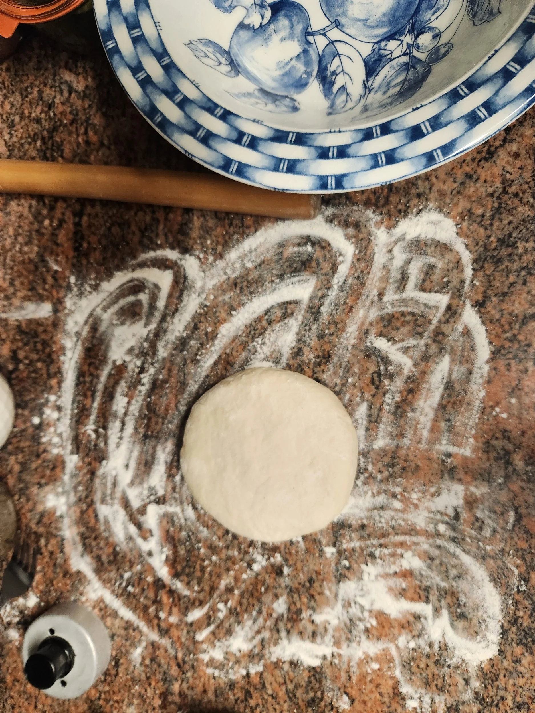 Dough ball flattened on floured surface