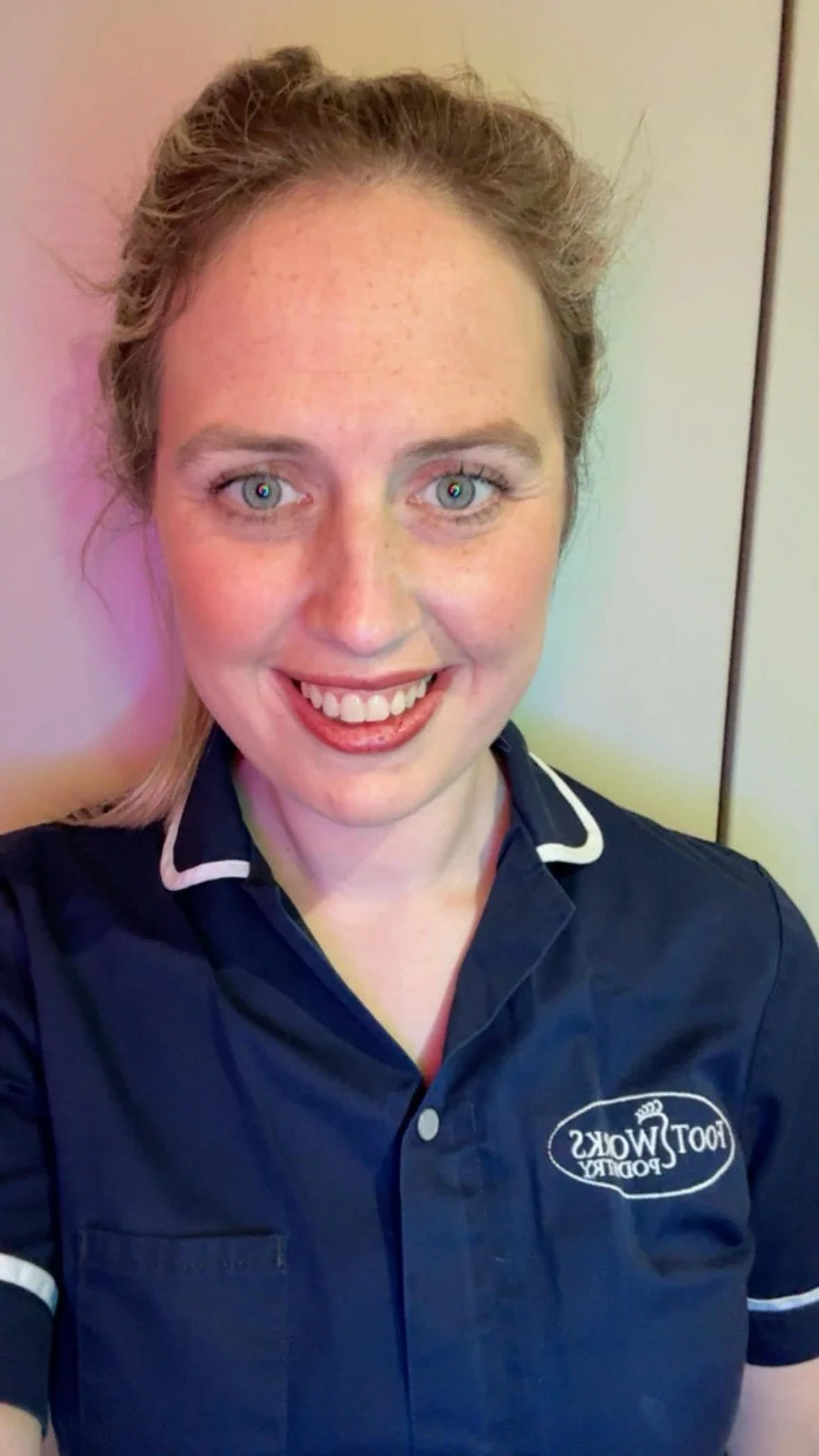 Sarah Laverty, HCPC registered podiatrist in Bangor Northern Ireland, wearing Foot Works Podiatry uniform and smiling in clinic.