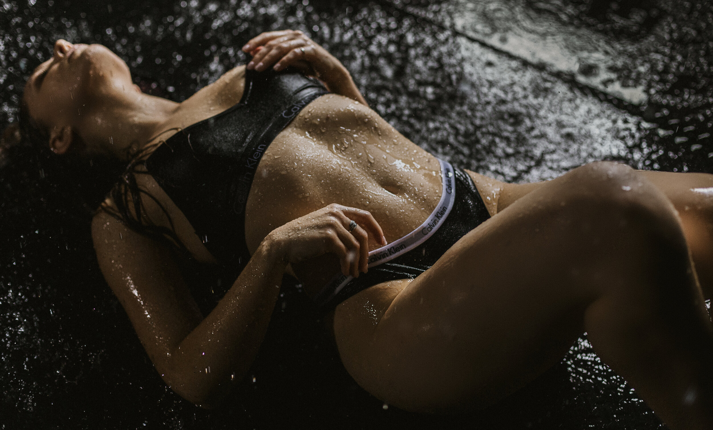 Southern California Boudoir Photography Of A Woman Laying Down Arching While Water Is Coming Down On Her Using Natural Light