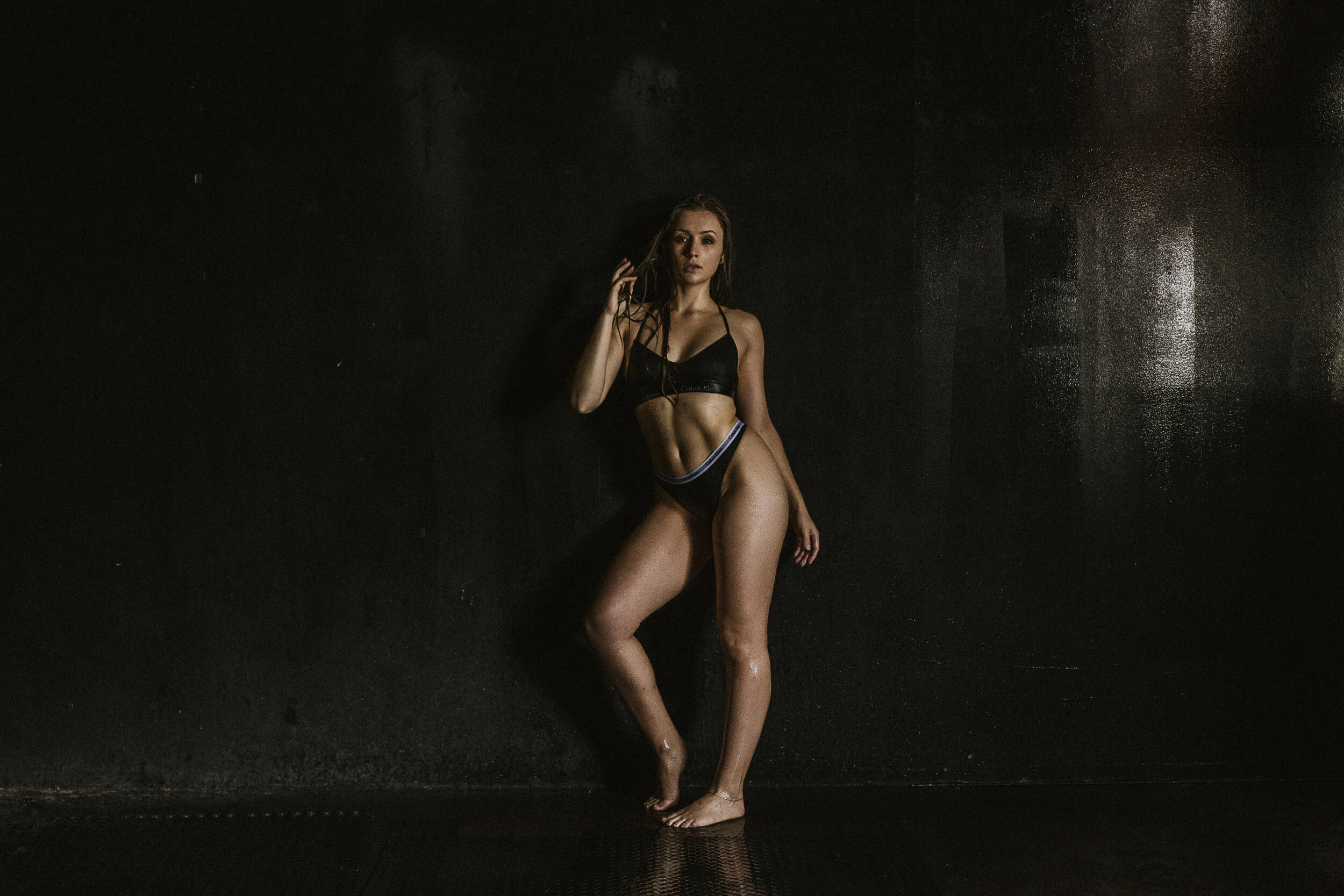Southern California Boudoir Photography Of A Woman Against A Black Wall Using Natural Light