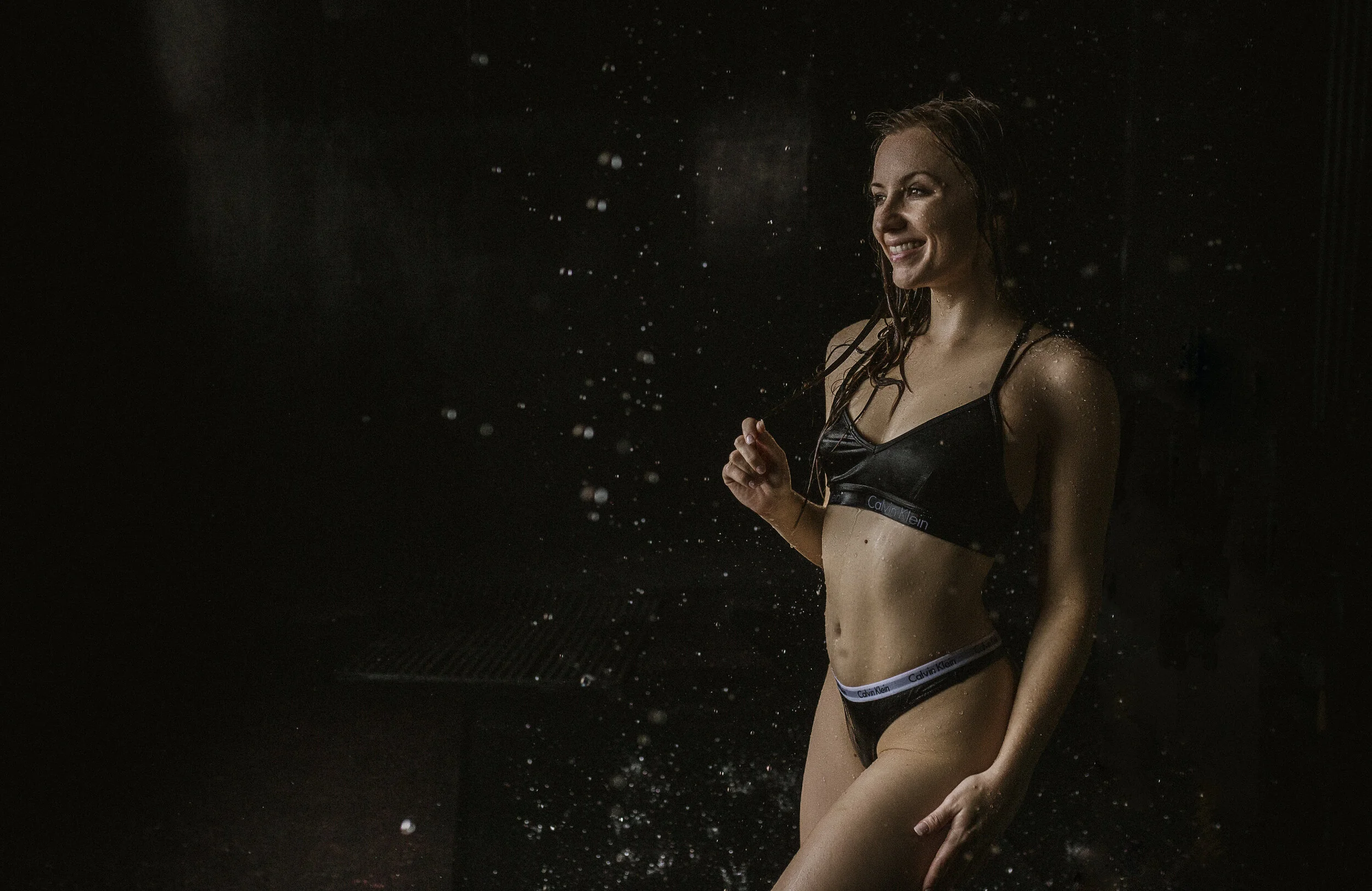 Southern California Boudoir Photography Of A Woman Smiling While Standing While Water Is Coming Down On Her Using Natural Light