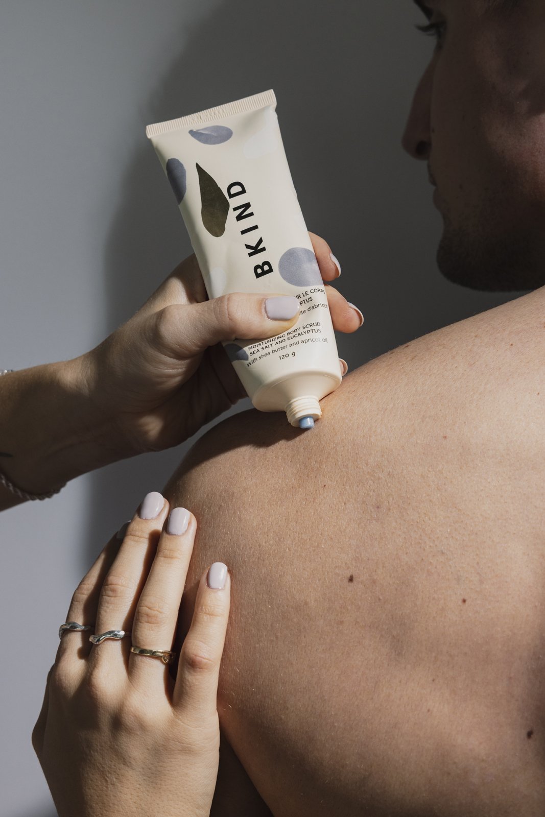 Une personne applique un gommage corporel hydratant sur son épaule.