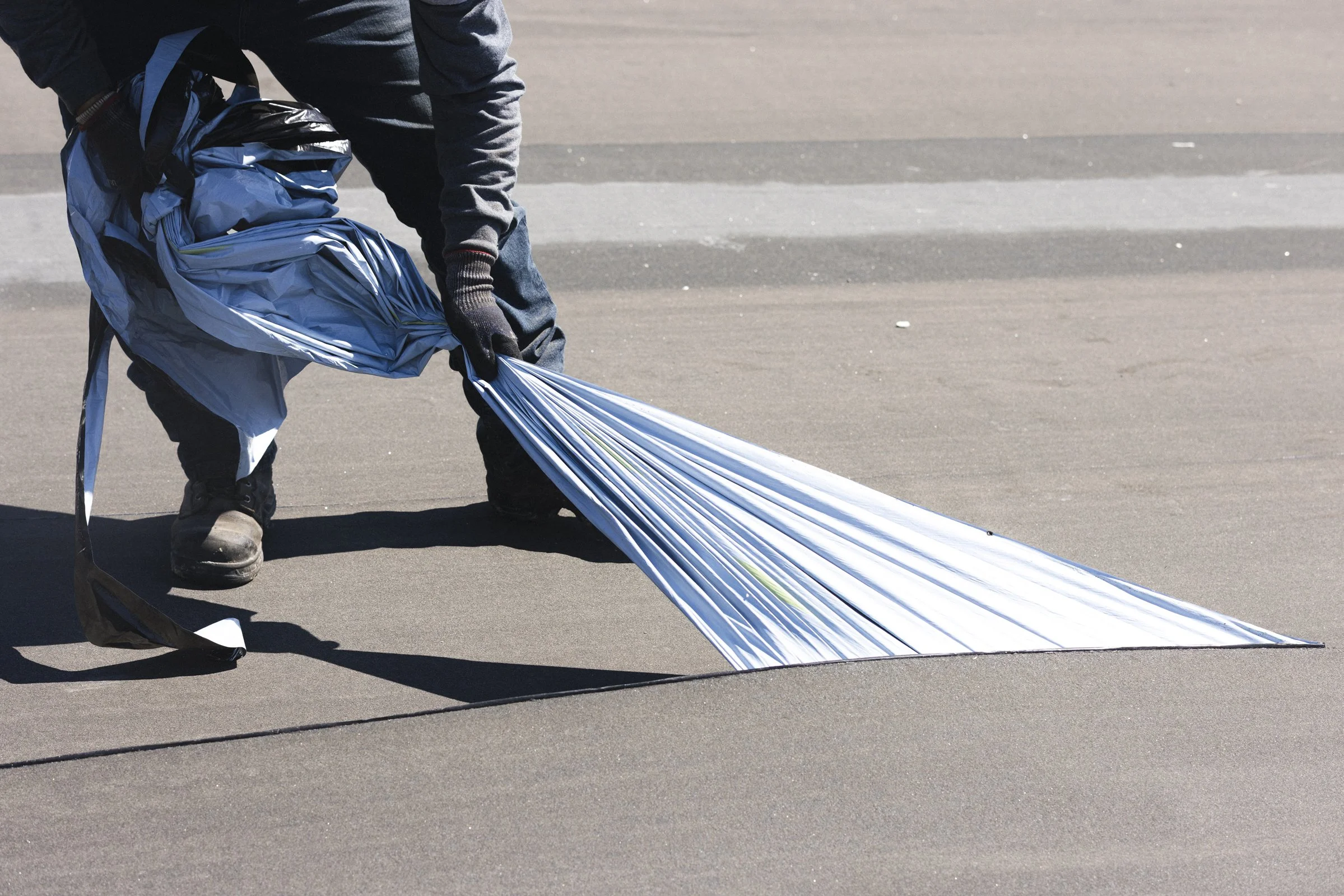 Une personne ramasse une vieille publicité ou un panneau publicitaire en aluminium dans une rue pavée.