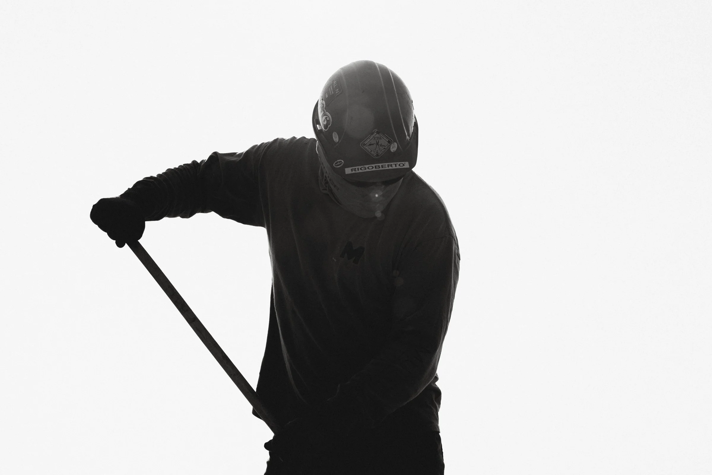 Silhouette d'un skieur portant un casque et tenant une barre, vu de côté contre un ciel clair.