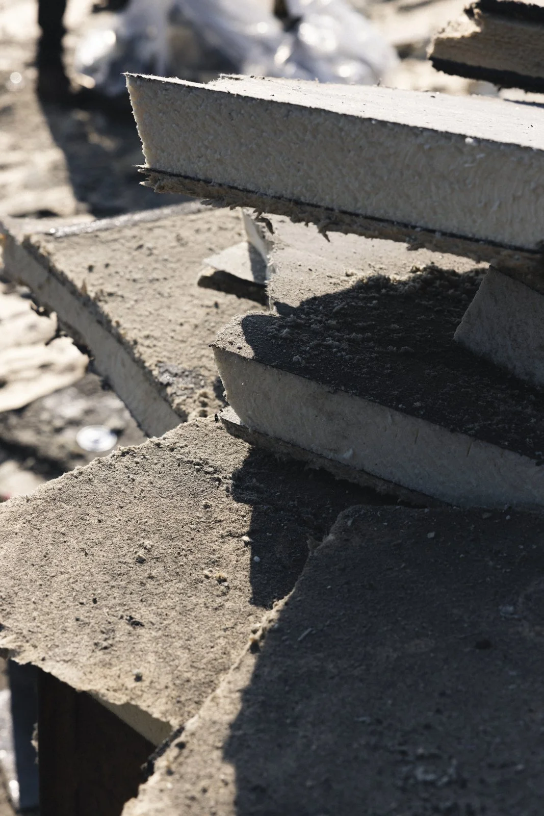 Vue rapprochée de morceaux de briques et de béton empilés, avec des ombres portées sous un éclairage naturel.