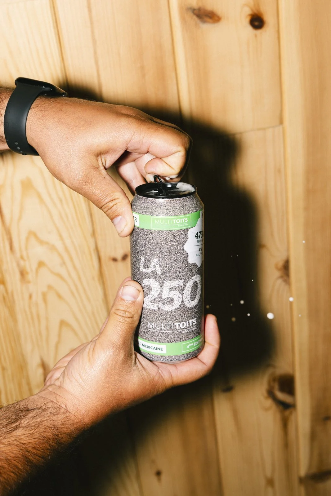 Mains tenant une canette de boisson, avec un fond en bois.