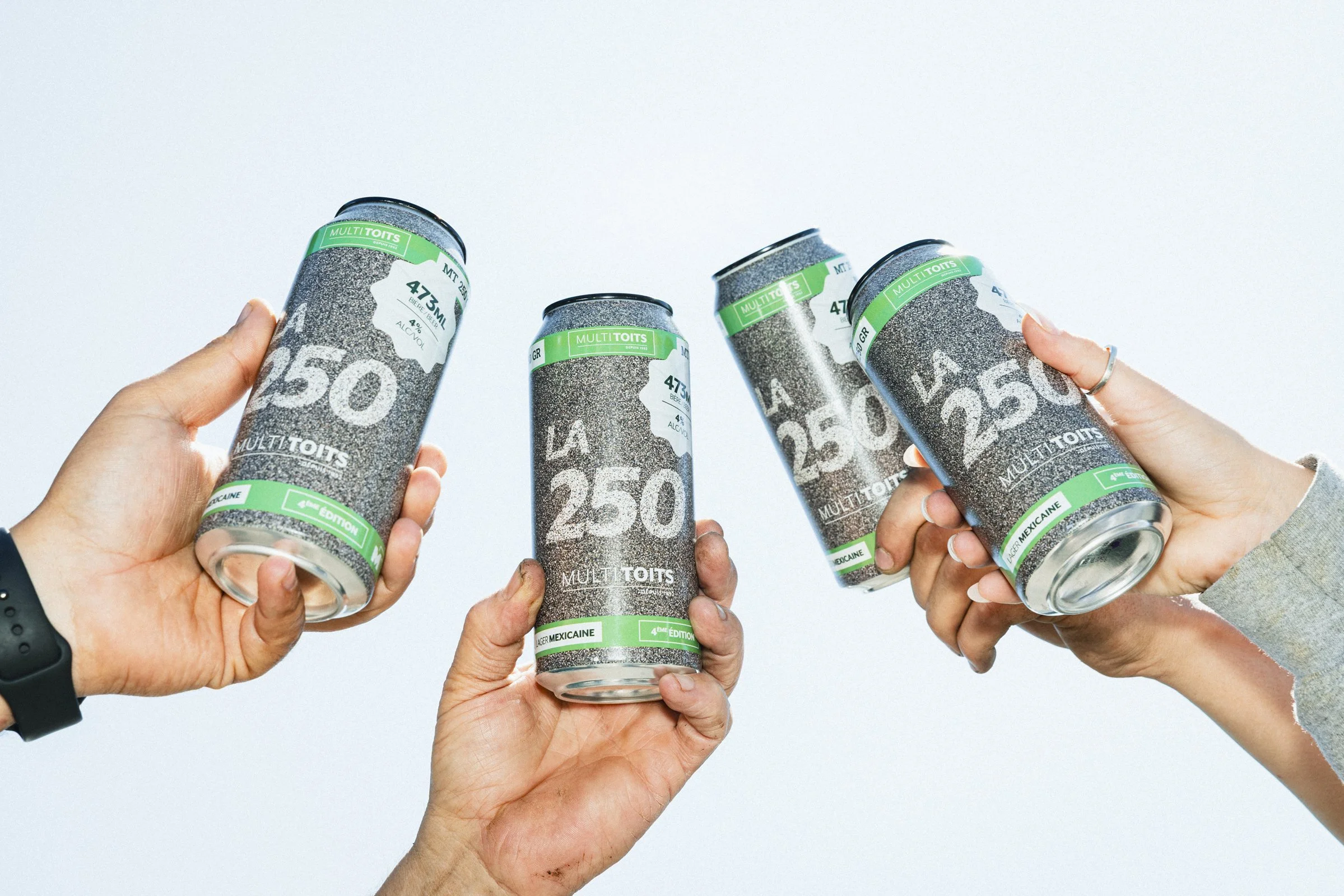 Groupe de quatre mains tenant des canettes de soda avec étiquettes vertes, blanches et noires, sur un fond blanc, avec texte 'LA 250' et 'MULTI TOITS'.