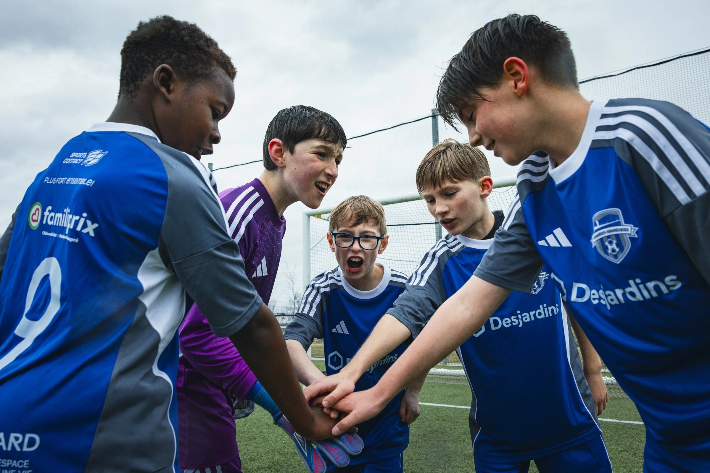 Jeune équipe de football masculine en cercle sur un terrain, se donnant une accolade avant un match ou une séance d'entraînement.