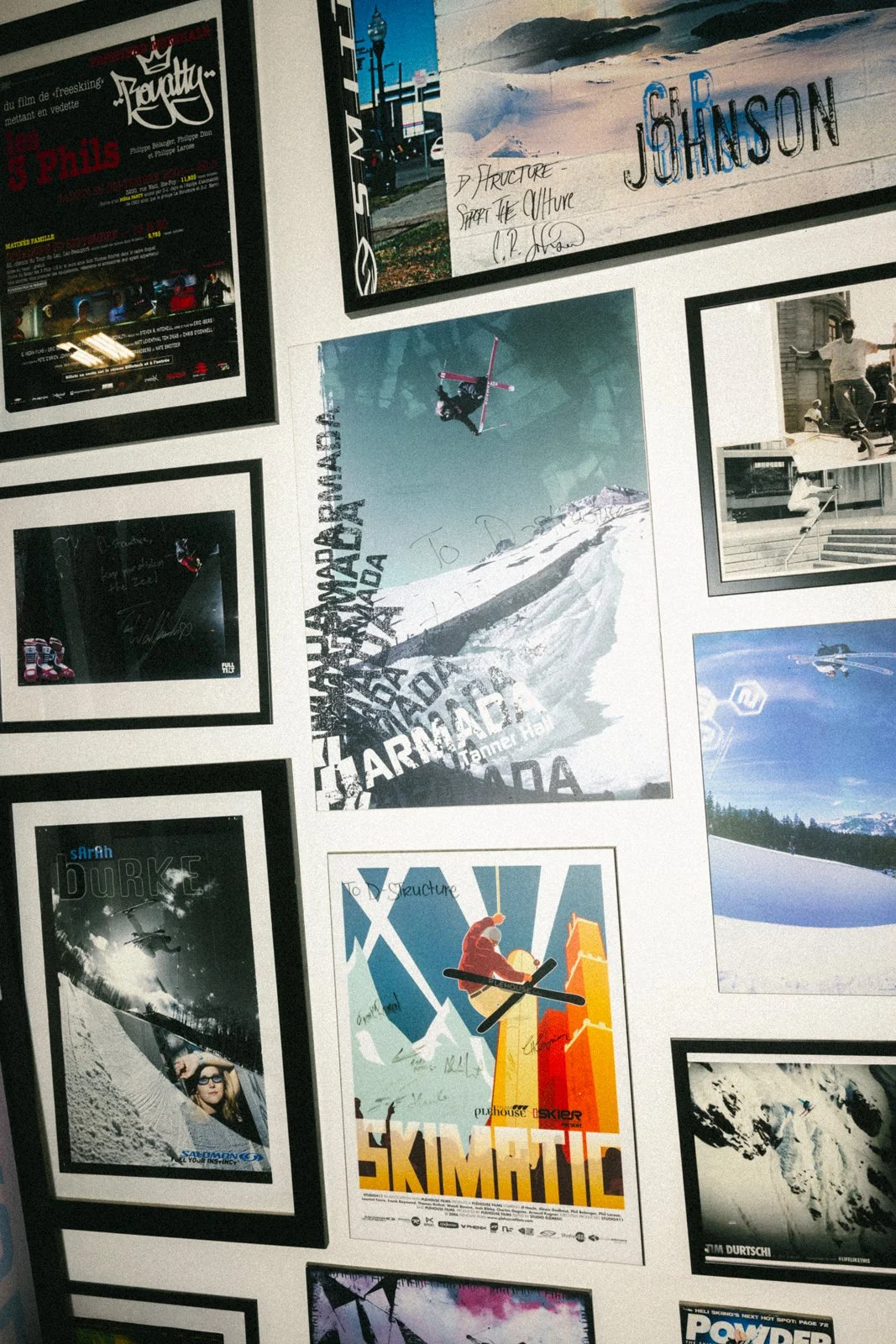 Affiches encadrées en milieu urbain, incluant une notice de film, une affiche de ski, des photographies de sports extrêmes et d'hiver, notamment du snowboard, du ski et des paysages enneigés.