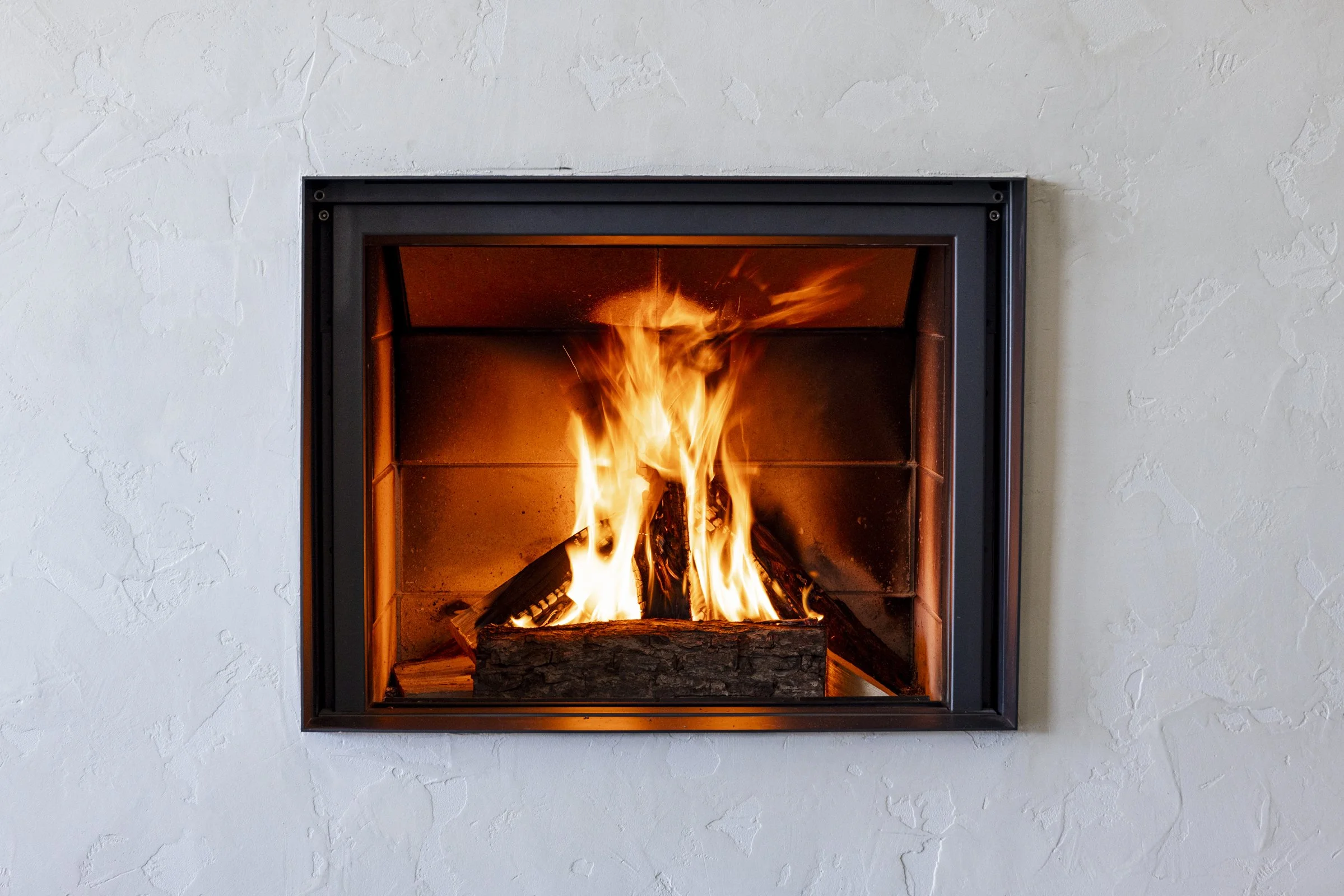 Cheminée avec feu de bois brillant dans un mur blanc