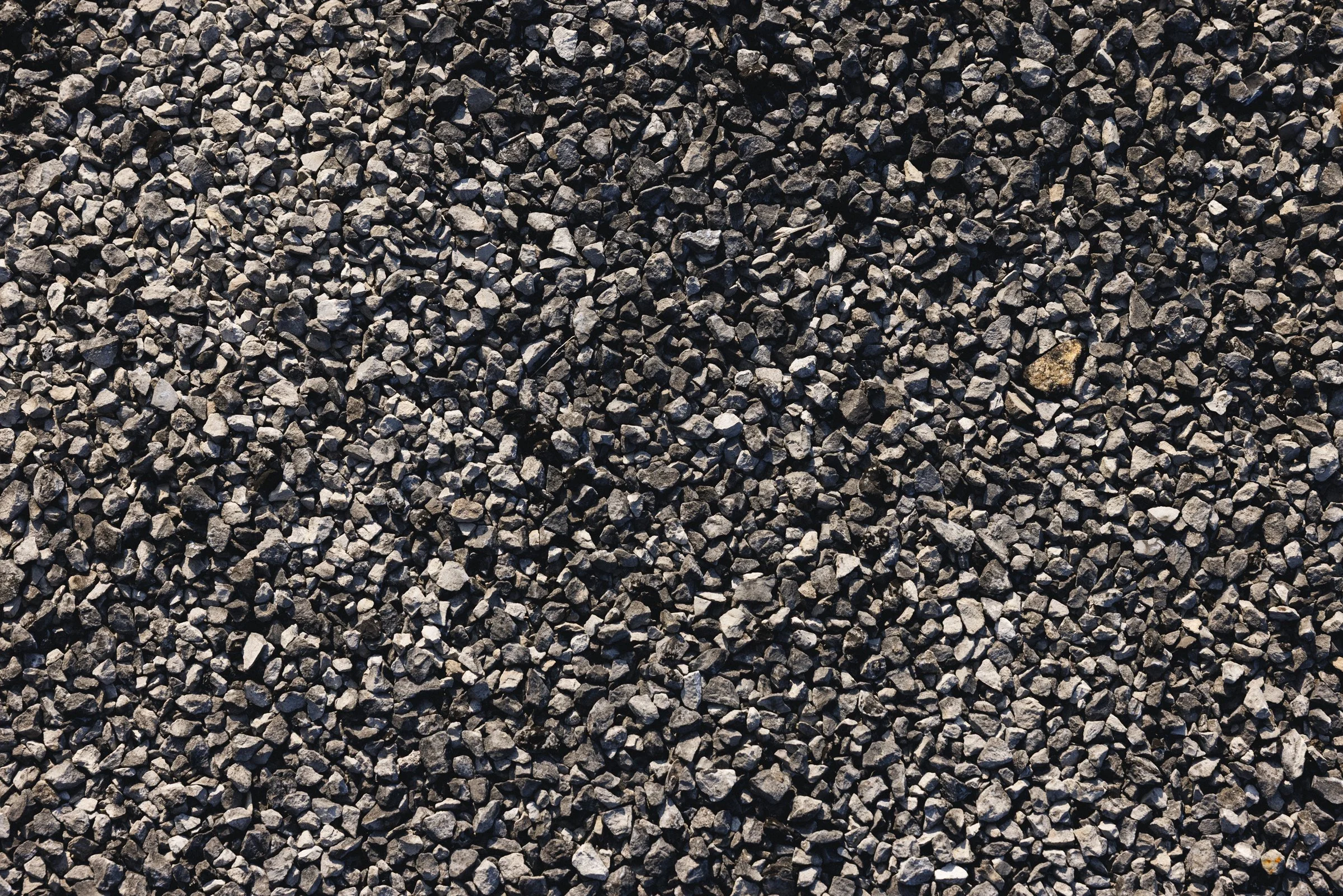 Gros plan de gravier ou petits cailloux noirs et gris dispersés uniformément.