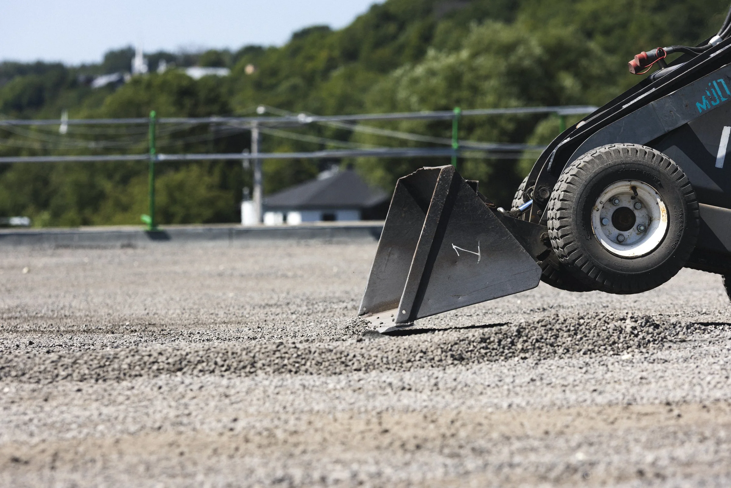 Une machine de chantier en train de niveler ou de préparer une surface en gravier ou en terre.