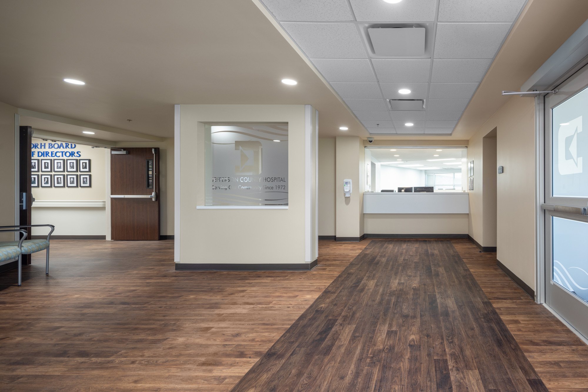 The Jefferson Hospital intake area is floored with laminate in warm wood tones.  The floor and ceiling pattern naturally moves the eye towards the sign in area.