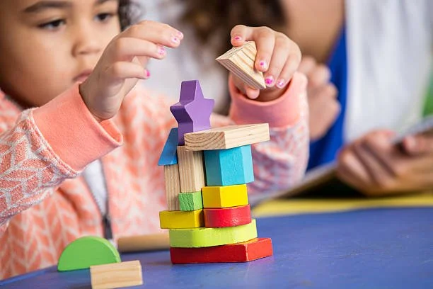 Children playing with colorful wooden building blocks on a blue table.