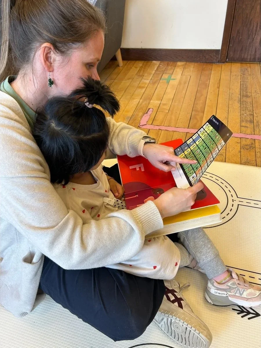 Woman and a young girl sitting on the floor looking at a periodic table chart.
