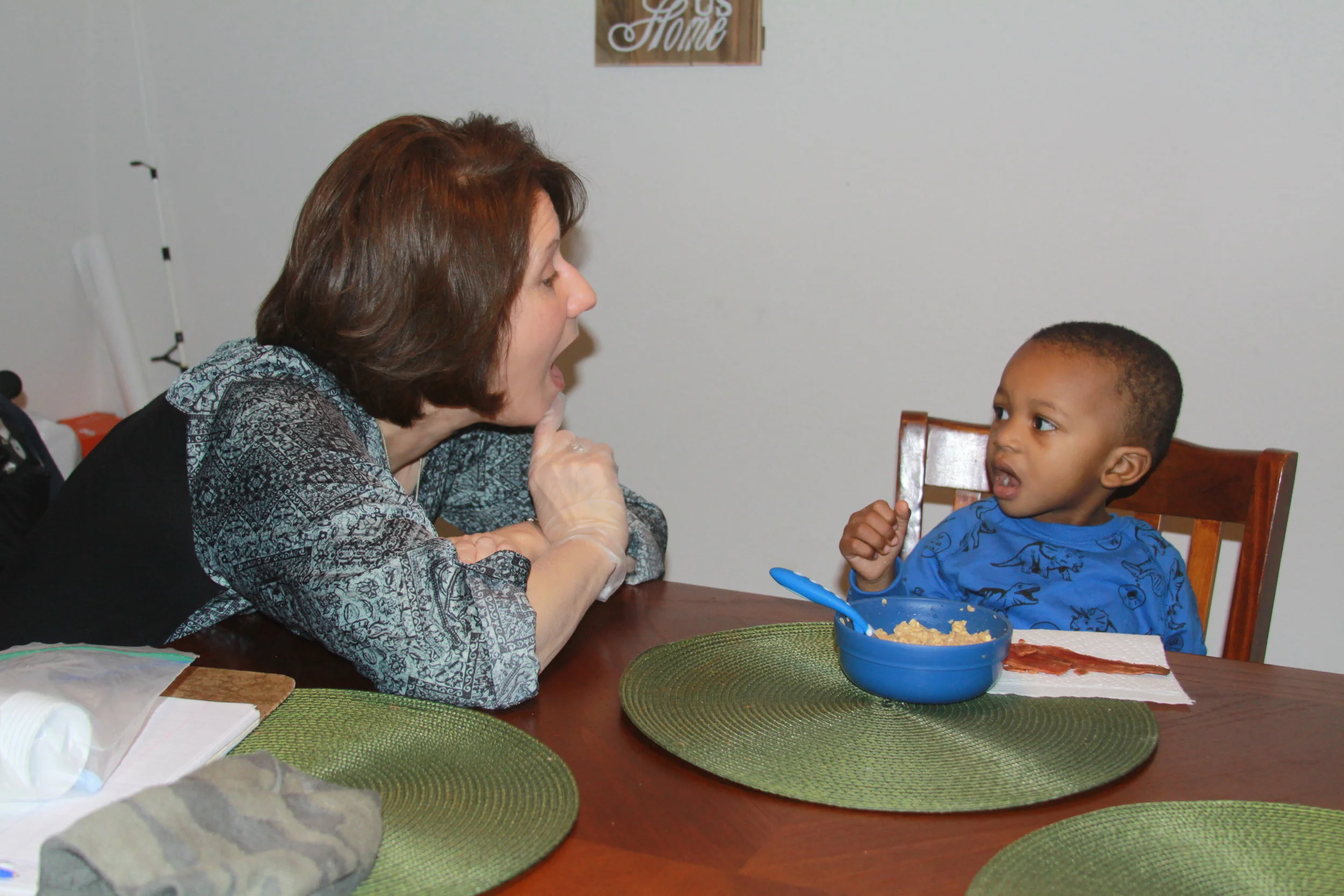 Child imitating Sherry's mouth movement during an in-home therapy session.
