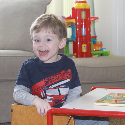 Child smiling while participating in a puzzle activity during speech therapy.