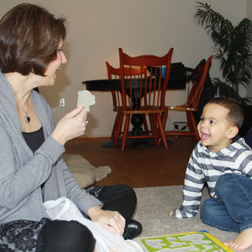 Sherry interacting with a child during a speech therapy puzzle activity.