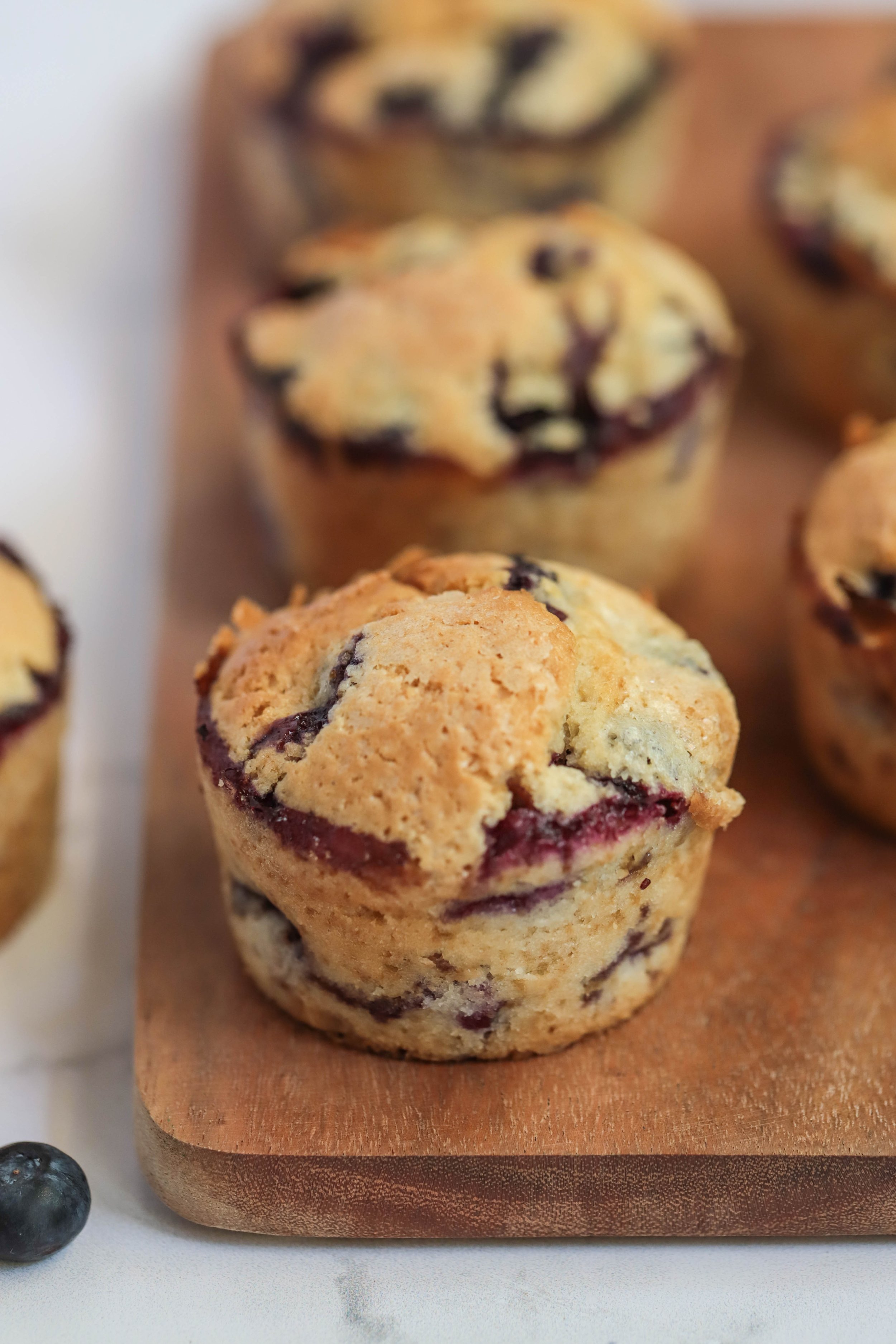 Vegan blueberry muffins side profile on a wooden cutting board