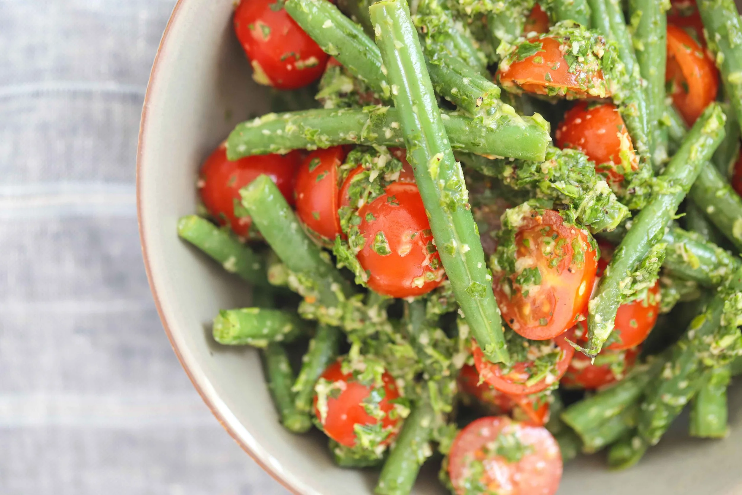 Cherry tomato and green bean salad on grey striped tablecloth