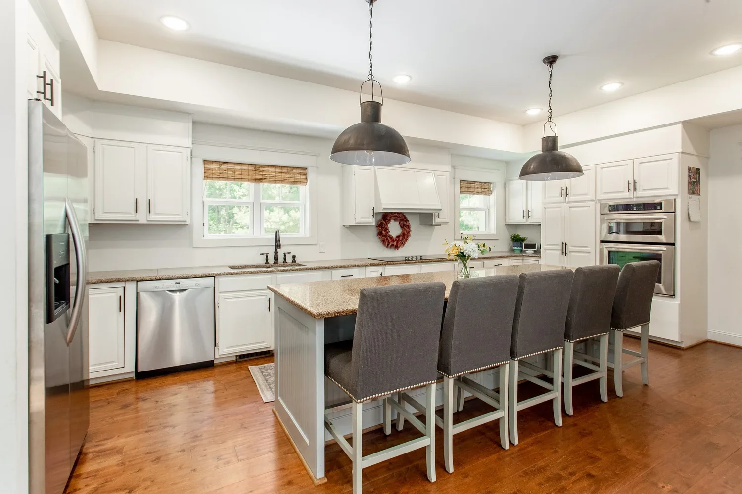 Renovated Lake Allatoona kitchen featuring white cabinetry, a large center island, industrial pendant lighting, and warm hardwood floors.