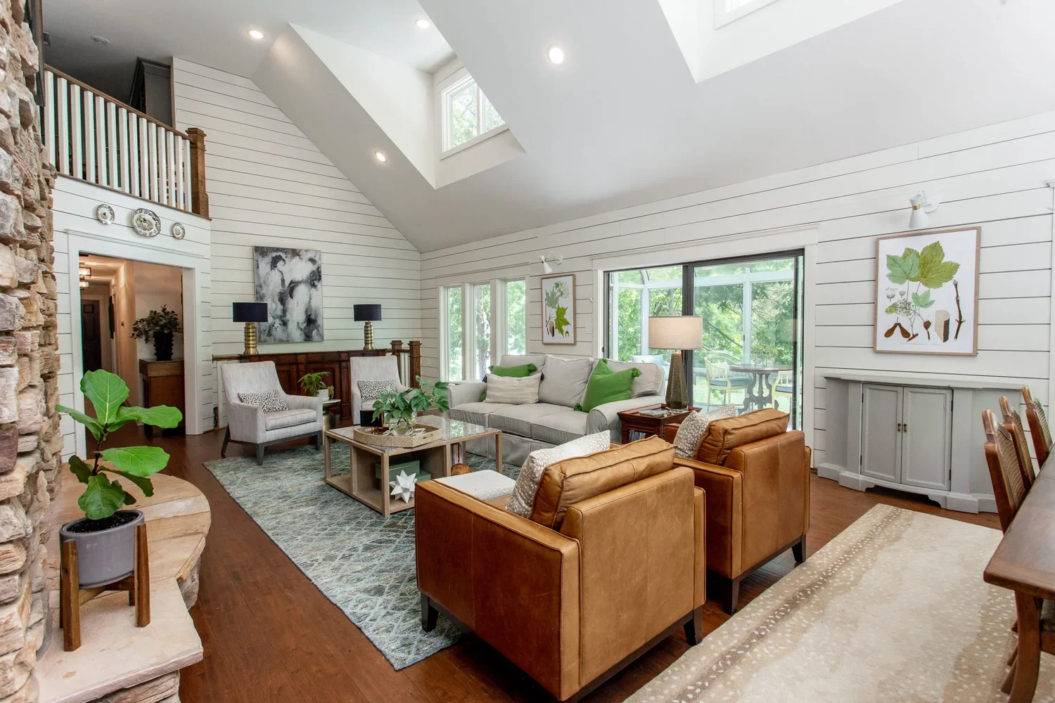 Lake Allatoona living room renovation featuring vaulted shiplap ceilings, skylights, warm leather seating, and bright natural light.